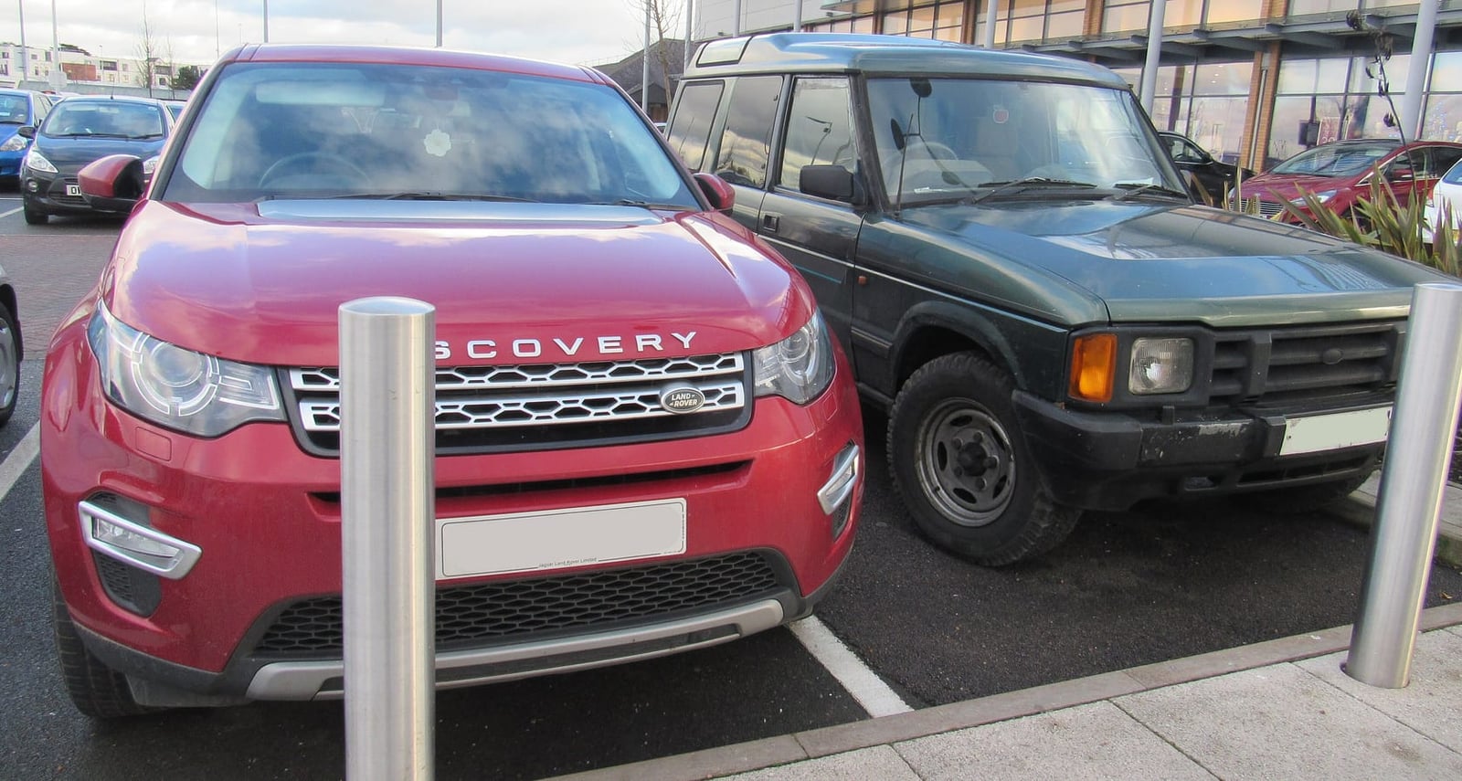 A 1994 Land Rover Discovery 1 parked beside a modern Discovery Sport in a car park