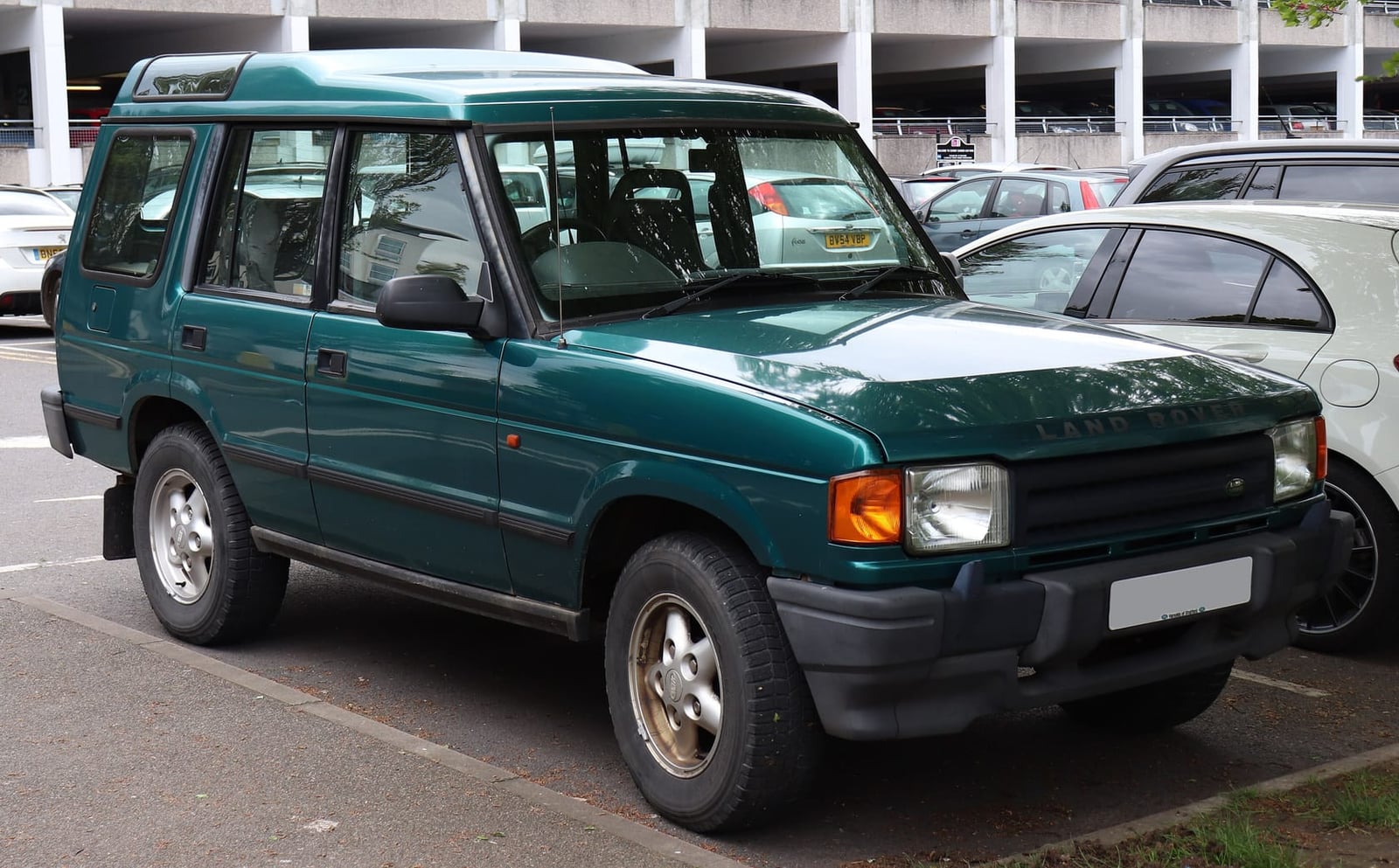 A teal 1990s Land Rover Discovery 1 five-door parked in a car park