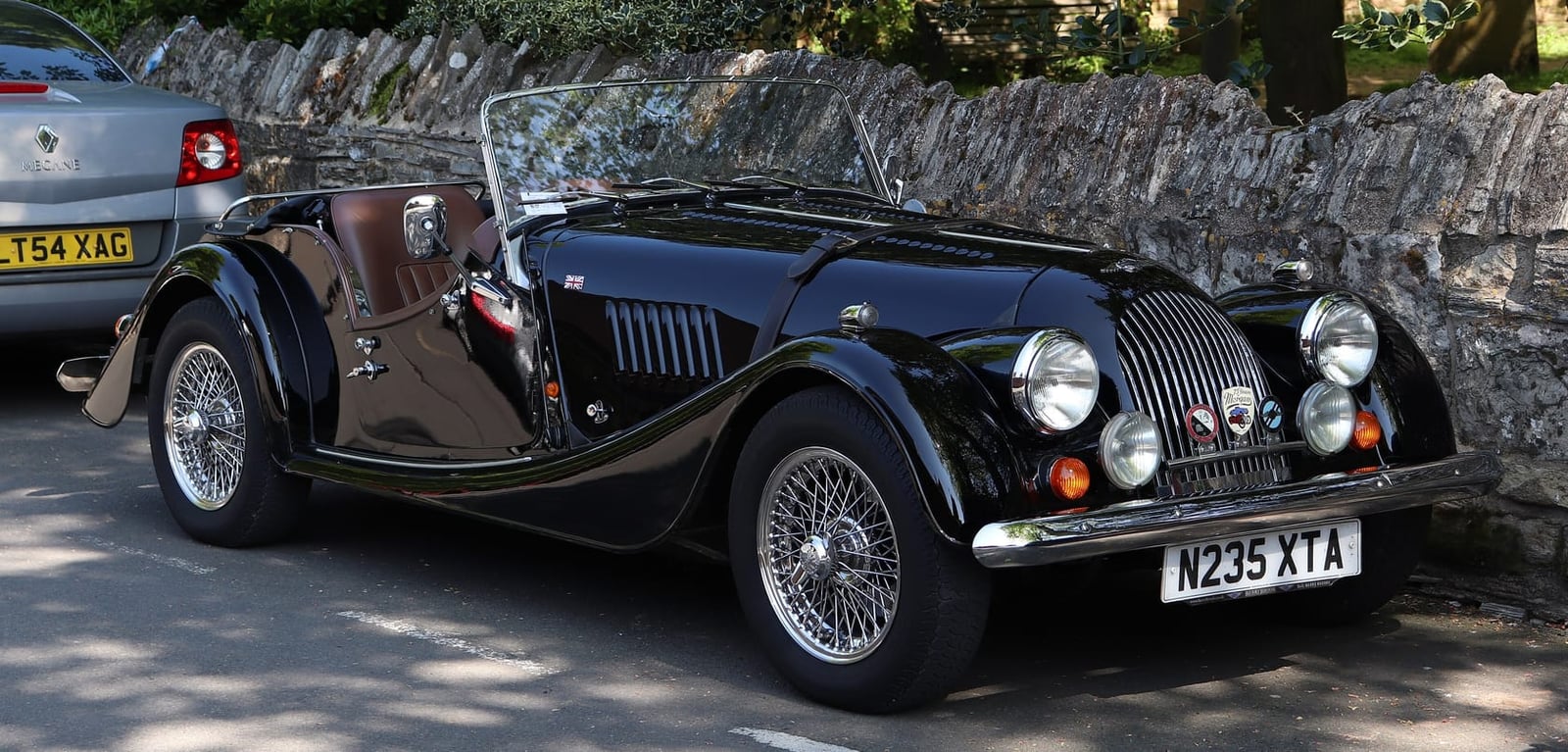 A black 1995 Morgan 4/4 1.8 parked beside a stone wall, front three-quarter view, UK registration N235 XTA