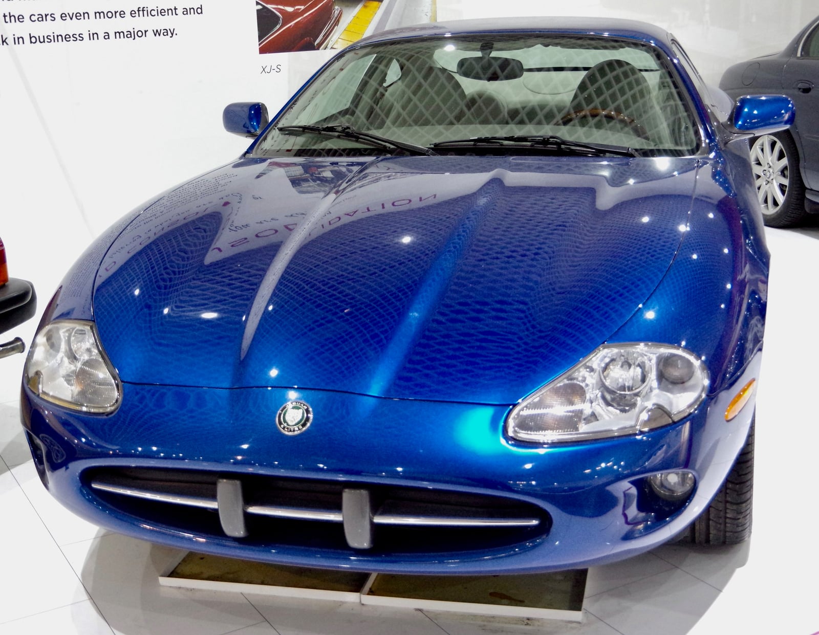 A blue 1996 Jaguar XK8 coupe, front view on display in a museum