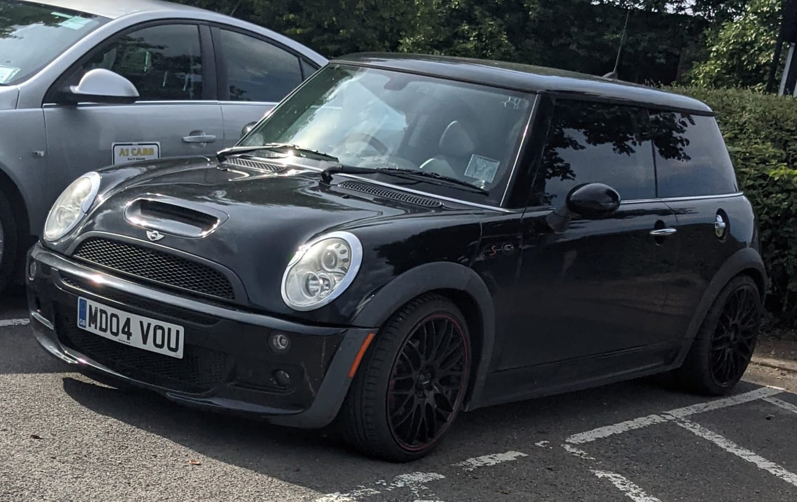 A black 2004 MINI Cooper S R53 with a UK registration and black alloy wheels parked in a car park