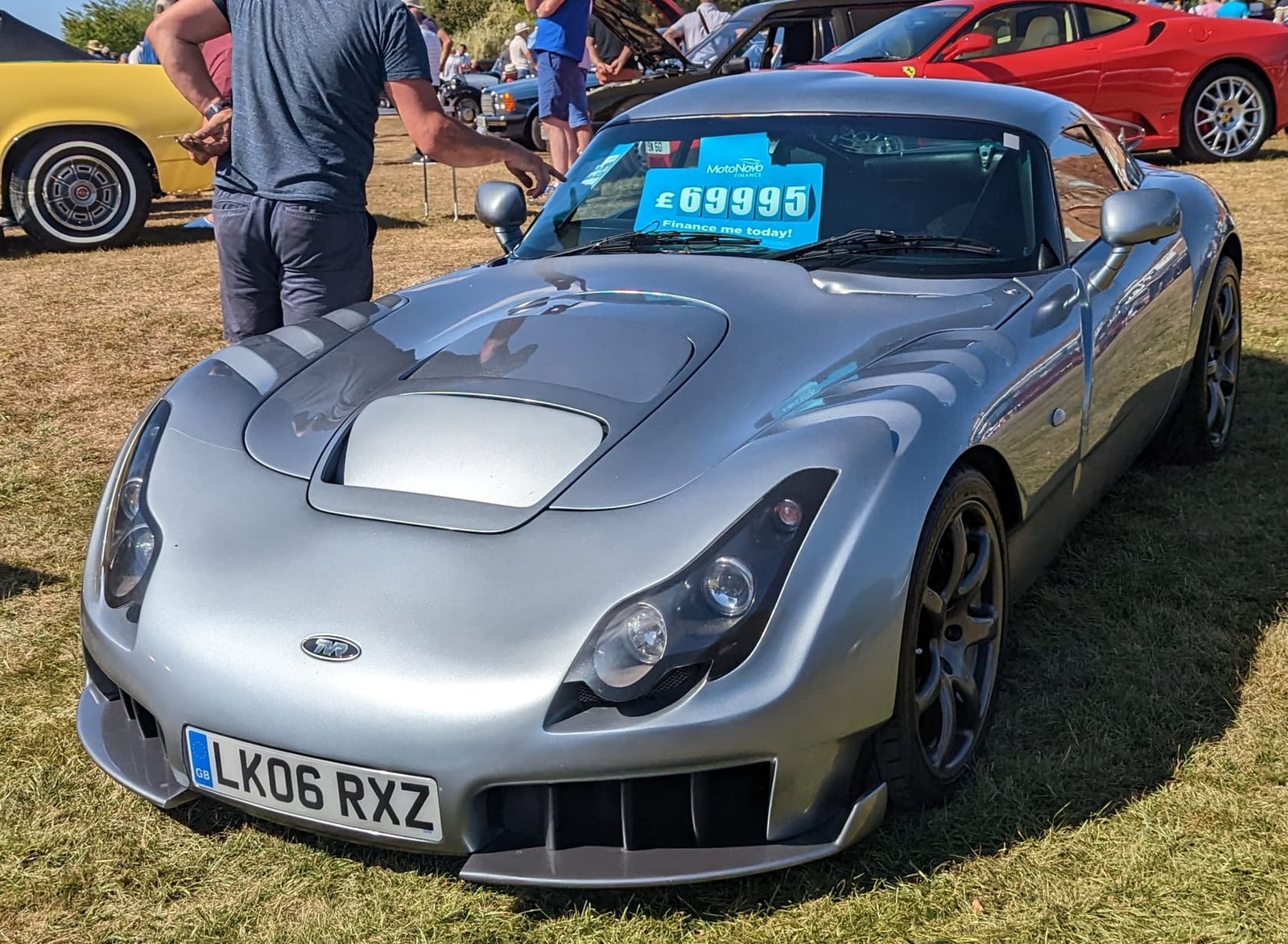 A silver 2006 TVR Sagaris with a UK registration parked among other cars at a show