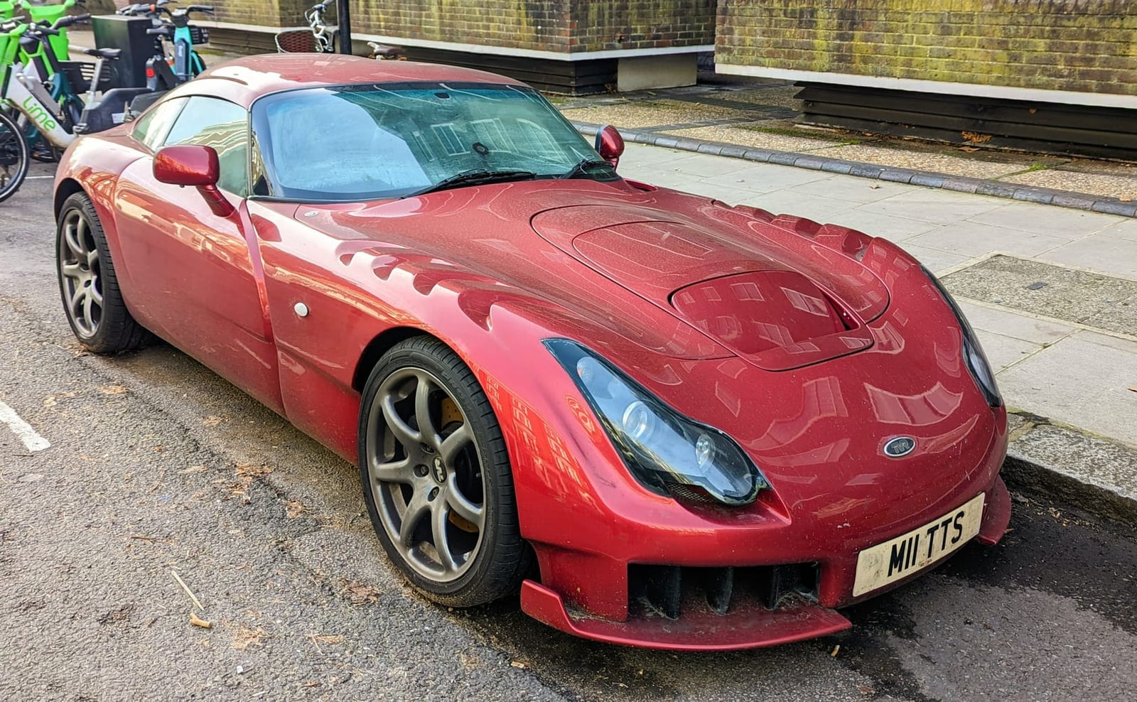 A red 2006 TVR Sagaris with a UK registration parked at a kerb in a town street