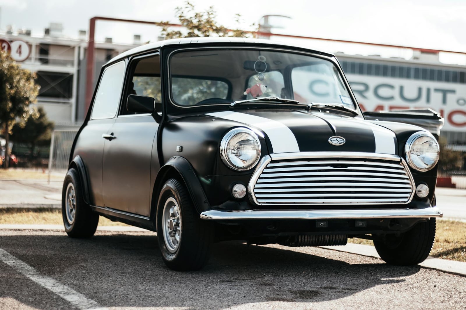 A black Mini Cooper S with white bonnet stripes and wide wheel-arch extensions, front three-quarter view
