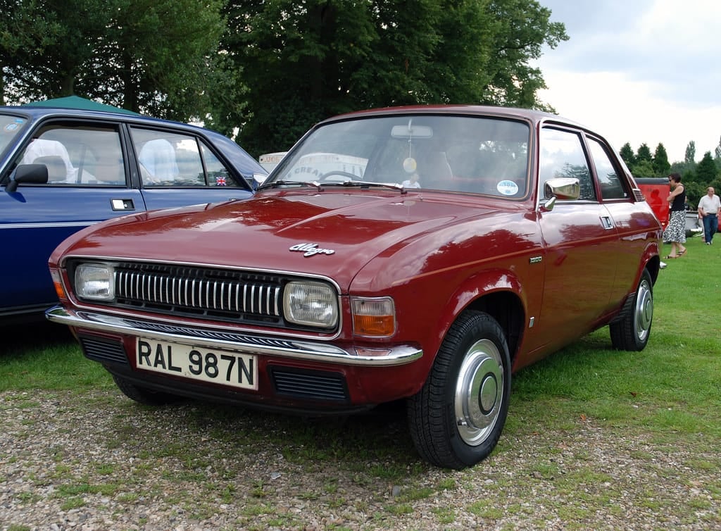 A red Austin Allegro parked on grass at a classic car show, front three-quarter view, UK registration RAL 987N