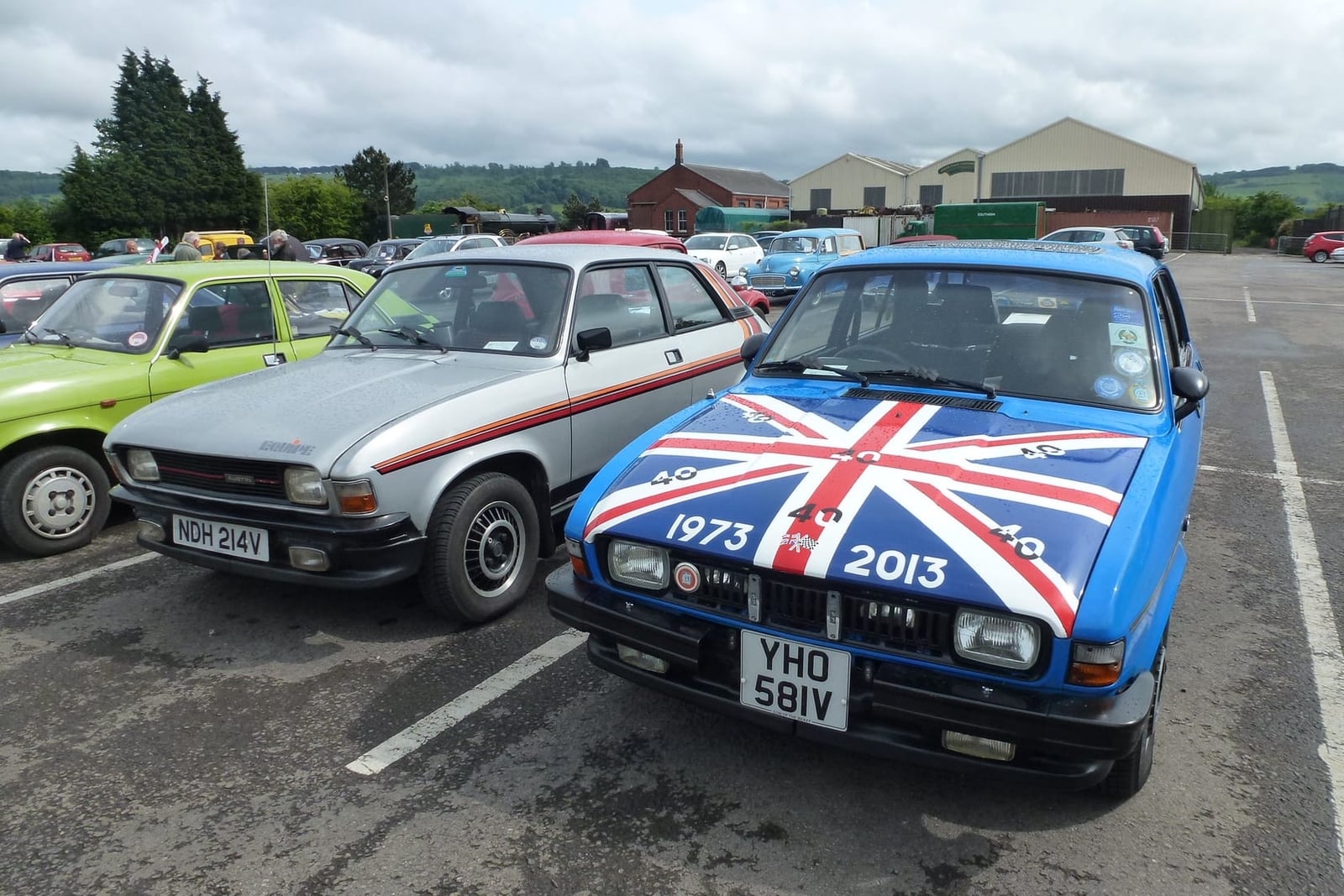 Three Austin Allegros in a show car park, one with a Union Jack painted bonnet marking the model's fortieth anniversary