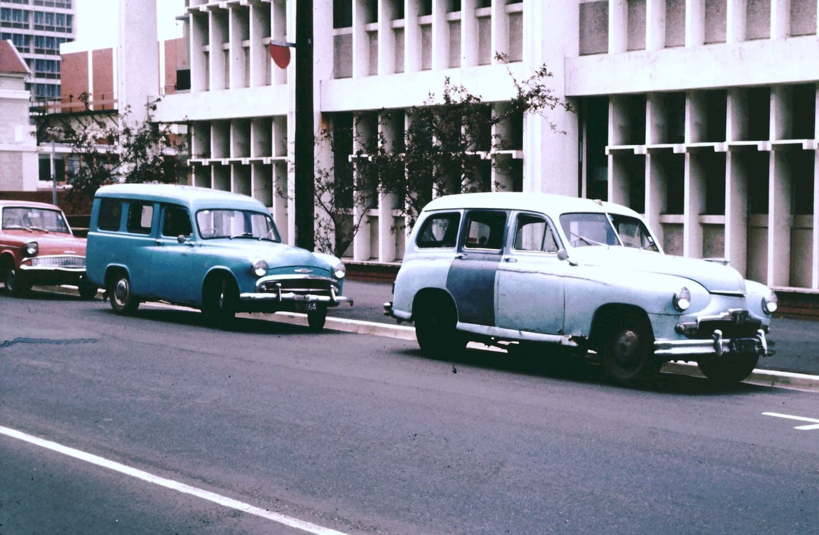 A period photograph of a street with a Standard Vanguard estate parked among other British cars of the day