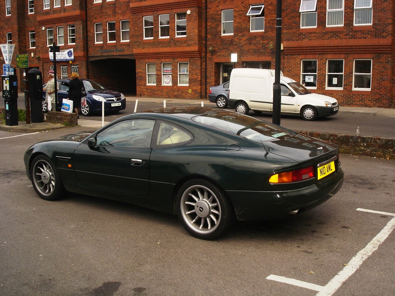 A British Racing Green Aston Martin DB7 coupe, rear three-quarter view parked on a street