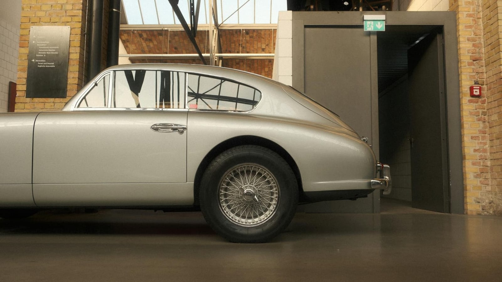 The rear of a silver Aston Martin DB2/4 showing the opening hatch window in a museum