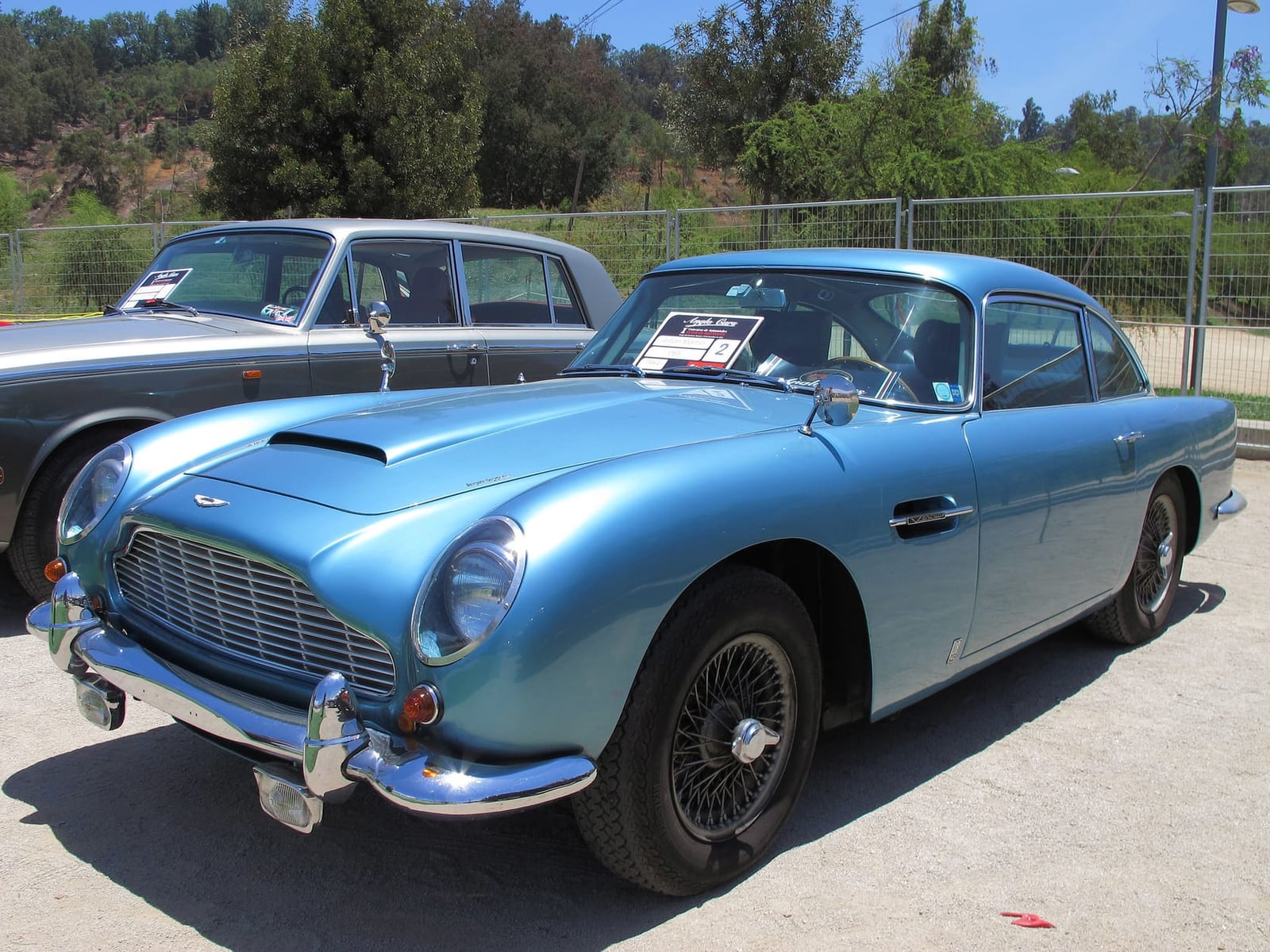 A light blue 1964 Aston Martin DB5 Vantage, front three-quarter view at a show