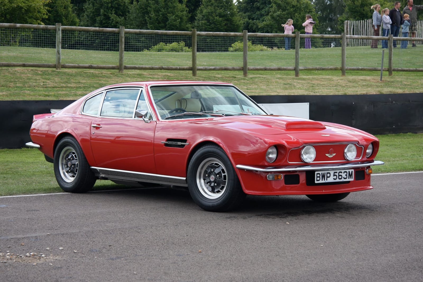 A red Aston Martin V8 Vantage with UK registration BHP 553M at a Goodwood event