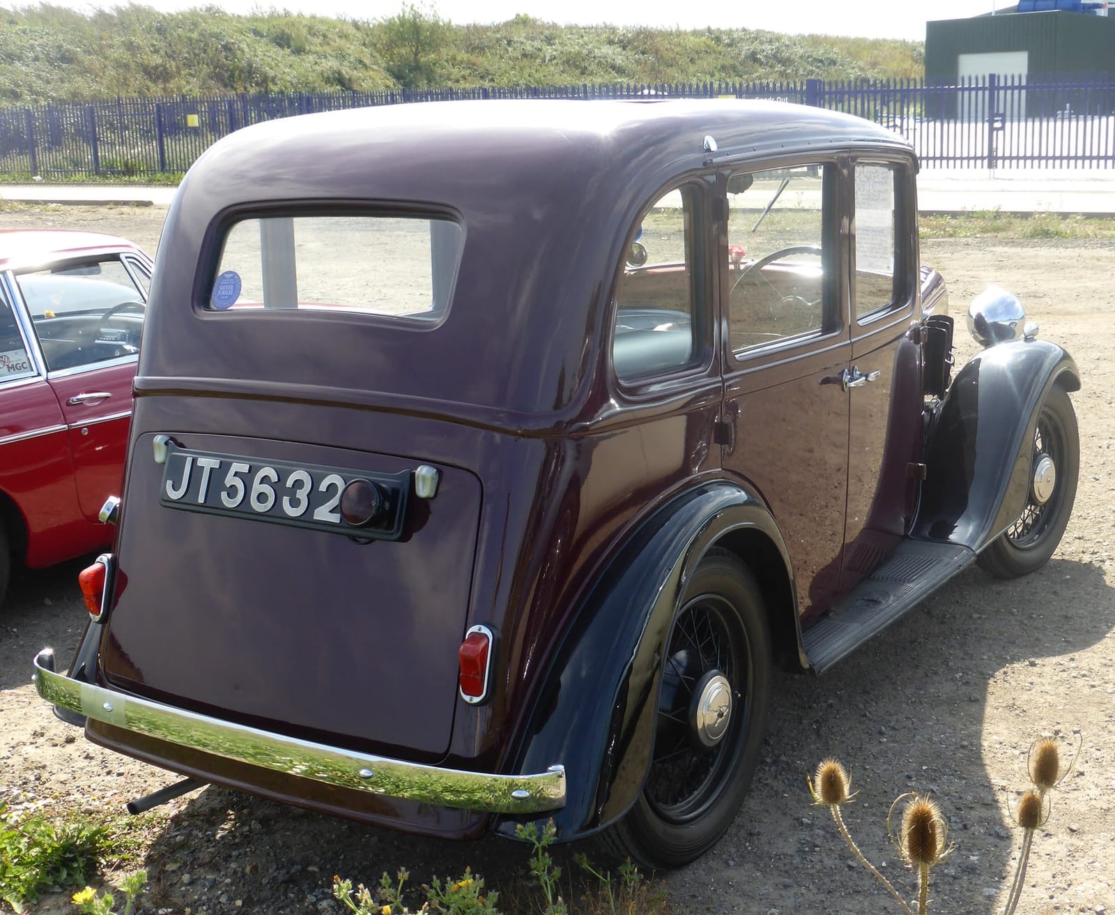 The rear three-quarter of a maroon 1936 Austin Ten Sherborne saloon in a car park
