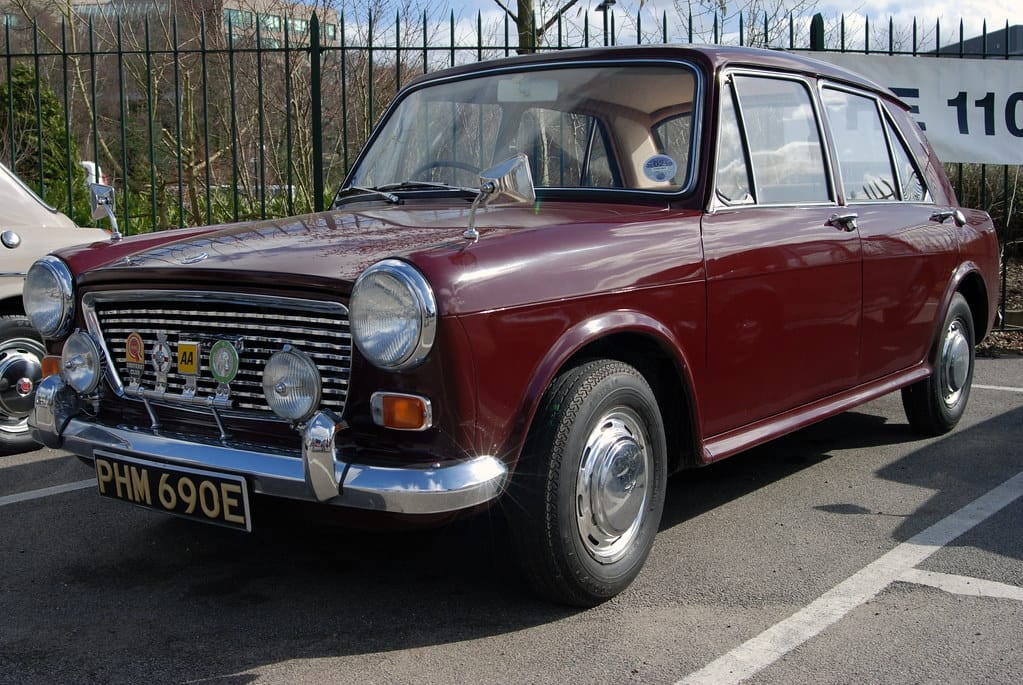 A maroon Austin 1300 parked on tarmac, front three-quarter view, UK registration PHM 690E