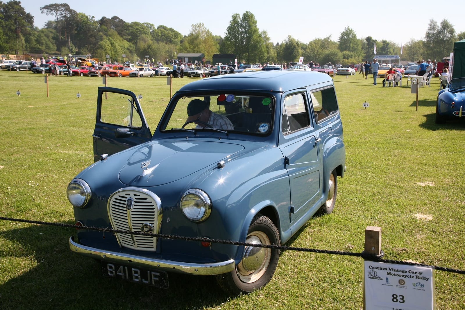 A blue Austin A35 Countryman estate with its doors open at a classic vehicle rally