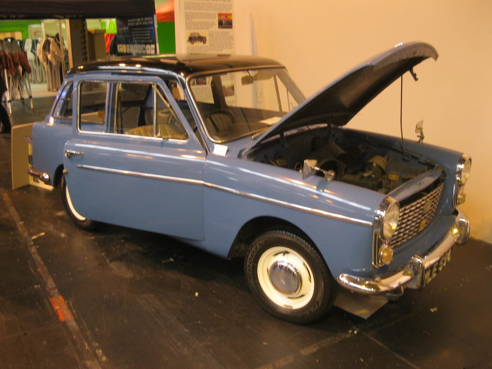 A blue Austin A40 Farina displayed in a museum with its bonnet raised
