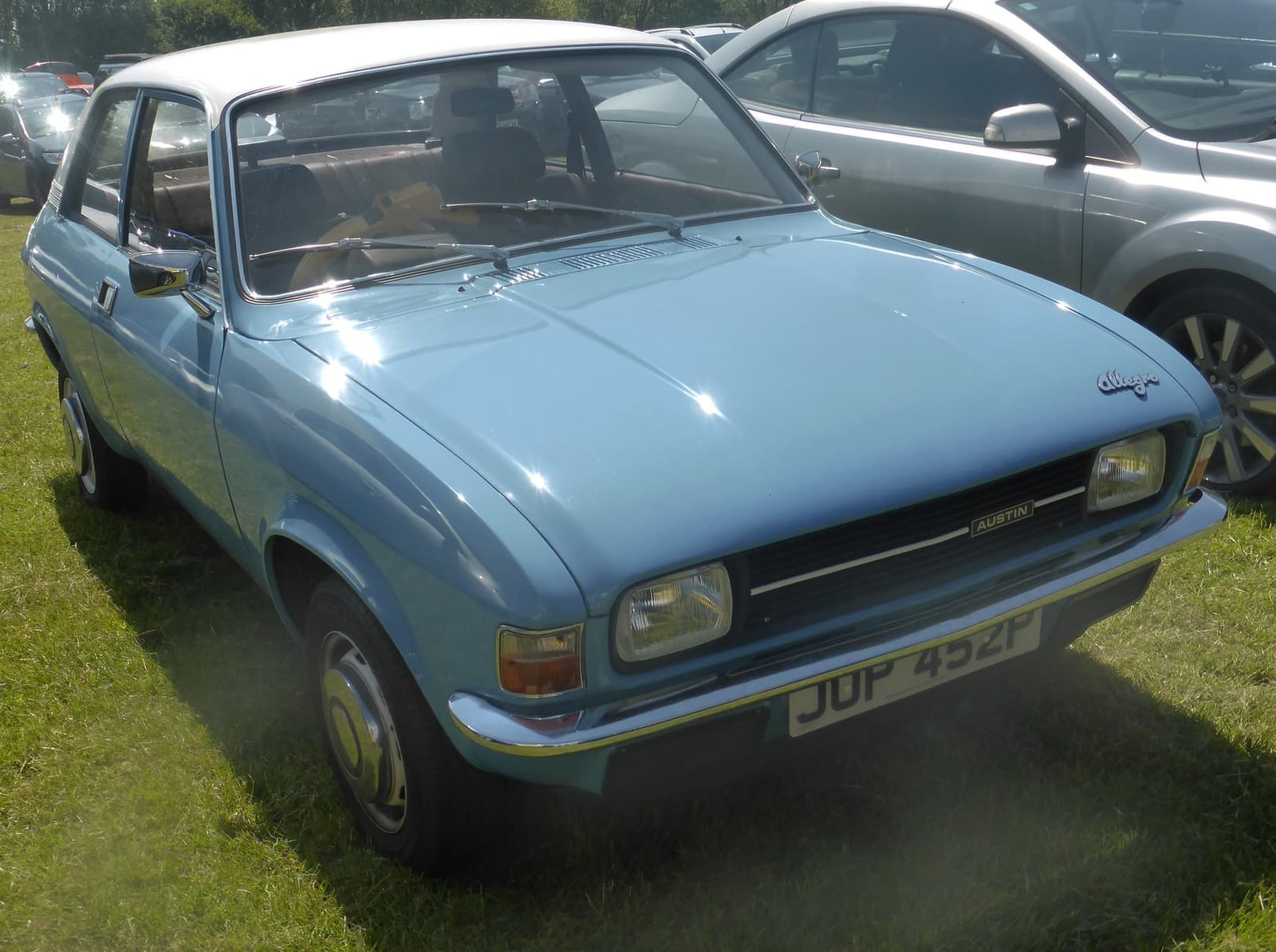 A maroon Austin Allegro two-door on grass at a classic car show, rear three-quarter view, UK registration KLF 252N