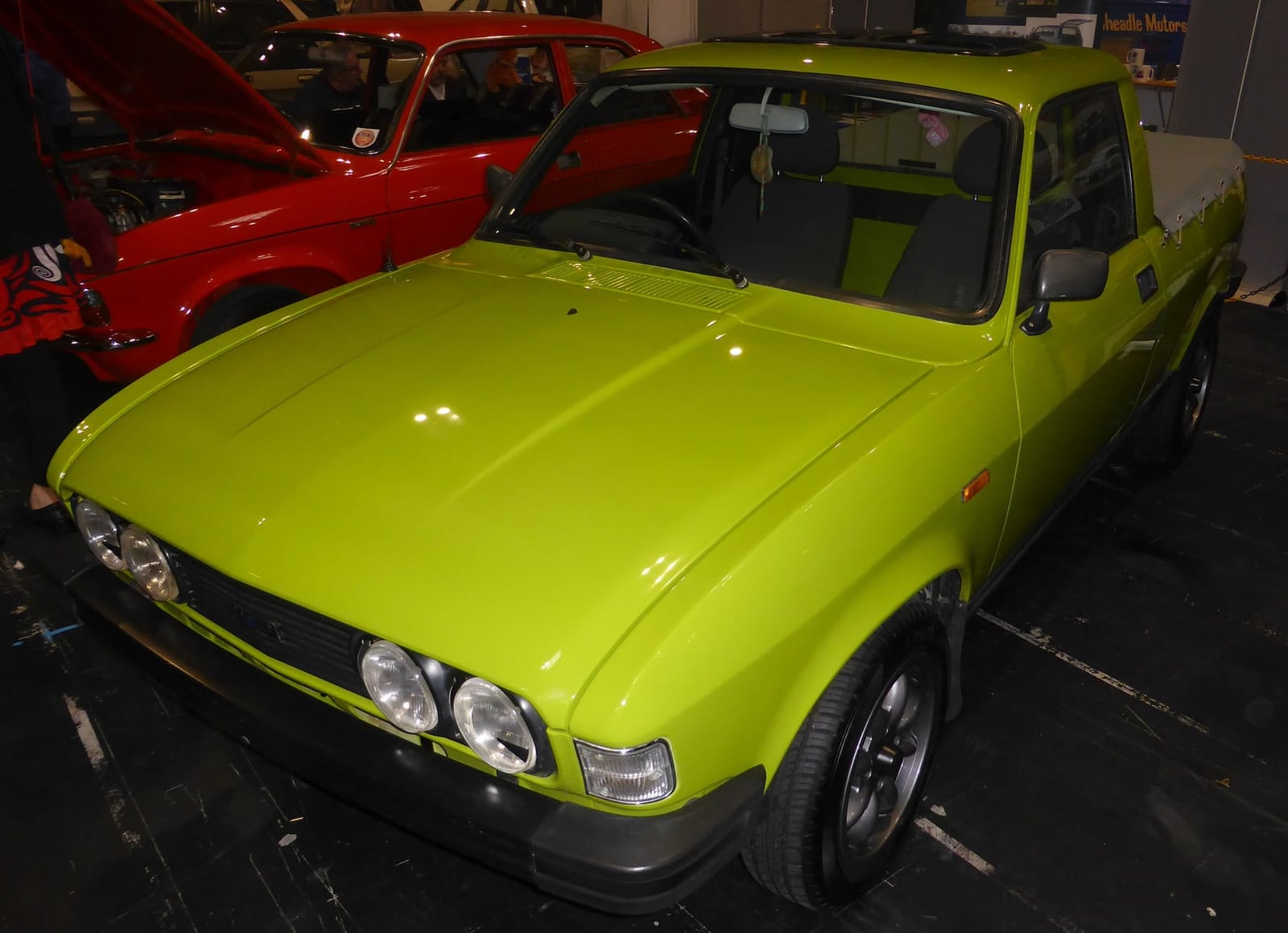 A bright green Austin Allegro converted into a pickup, on indoor display, front three-quarter view
