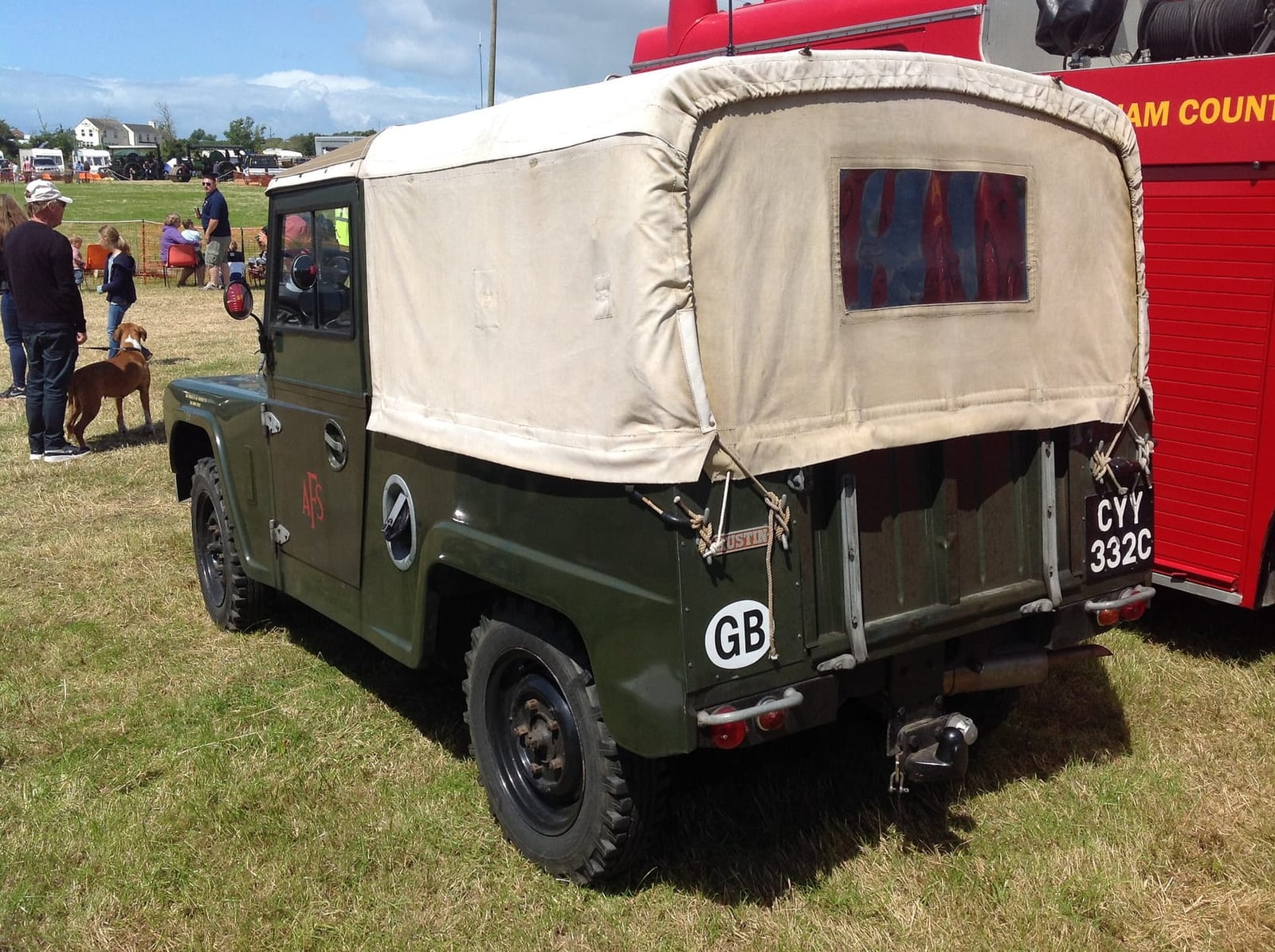 A green Austin Gipsy four-wheel-drive utility with a canvas tilt on grass at a vehicle show, UK registration CYY 332C