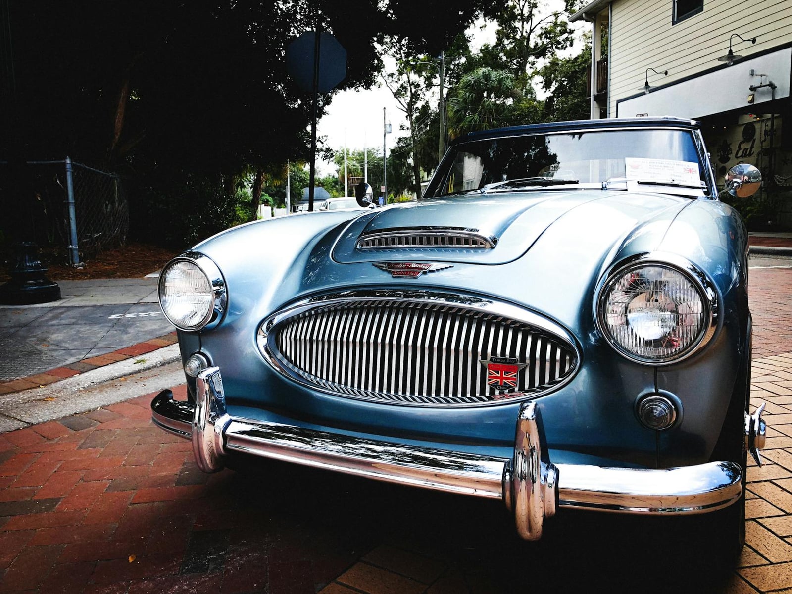 A light blue Austin-Healey 3000 head-on, showing the curved chrome grille and a Union Jack badge