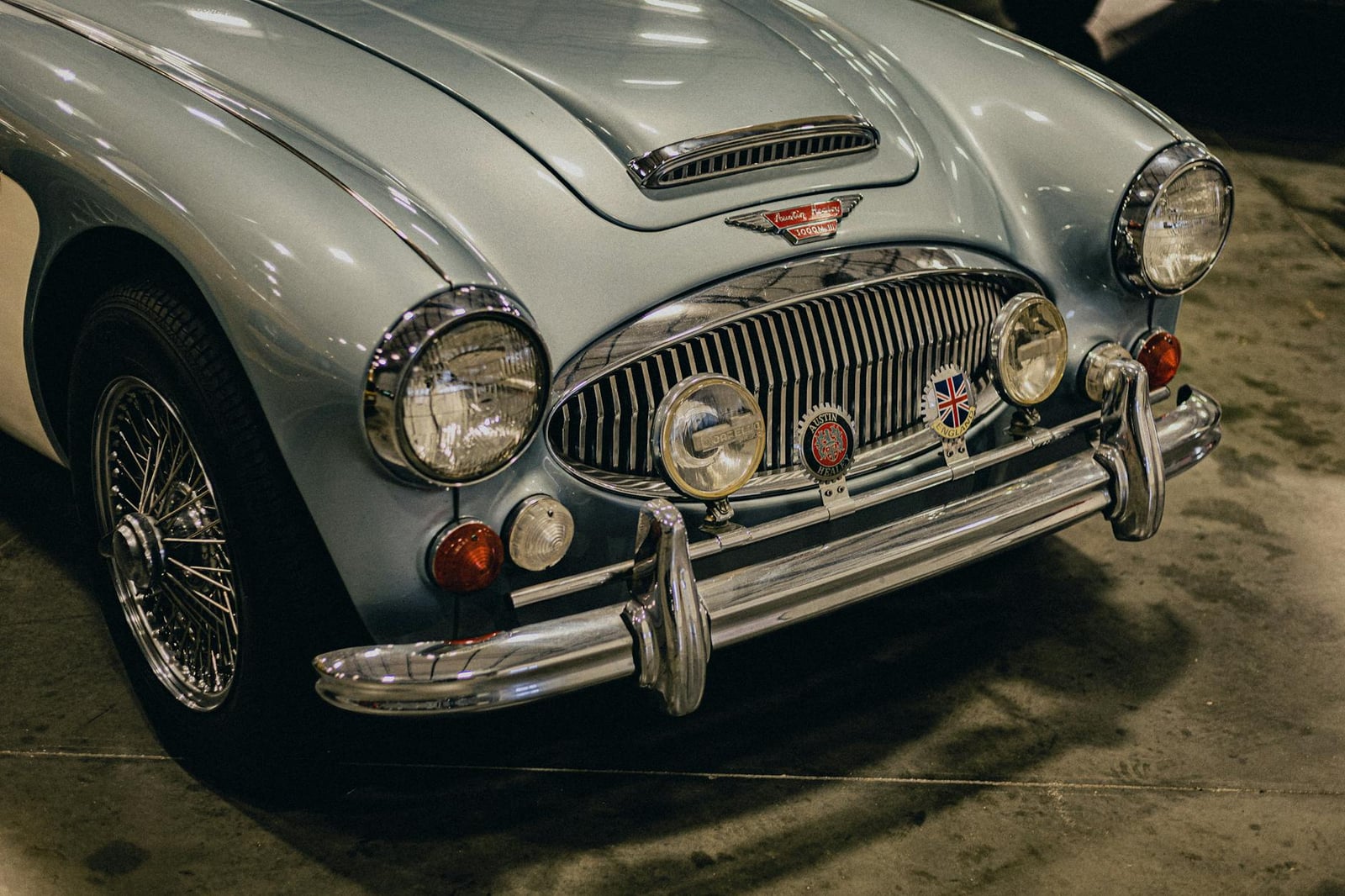 The front of a light blue Austin-Healey 3000 with wire wheels and chrome bumpers