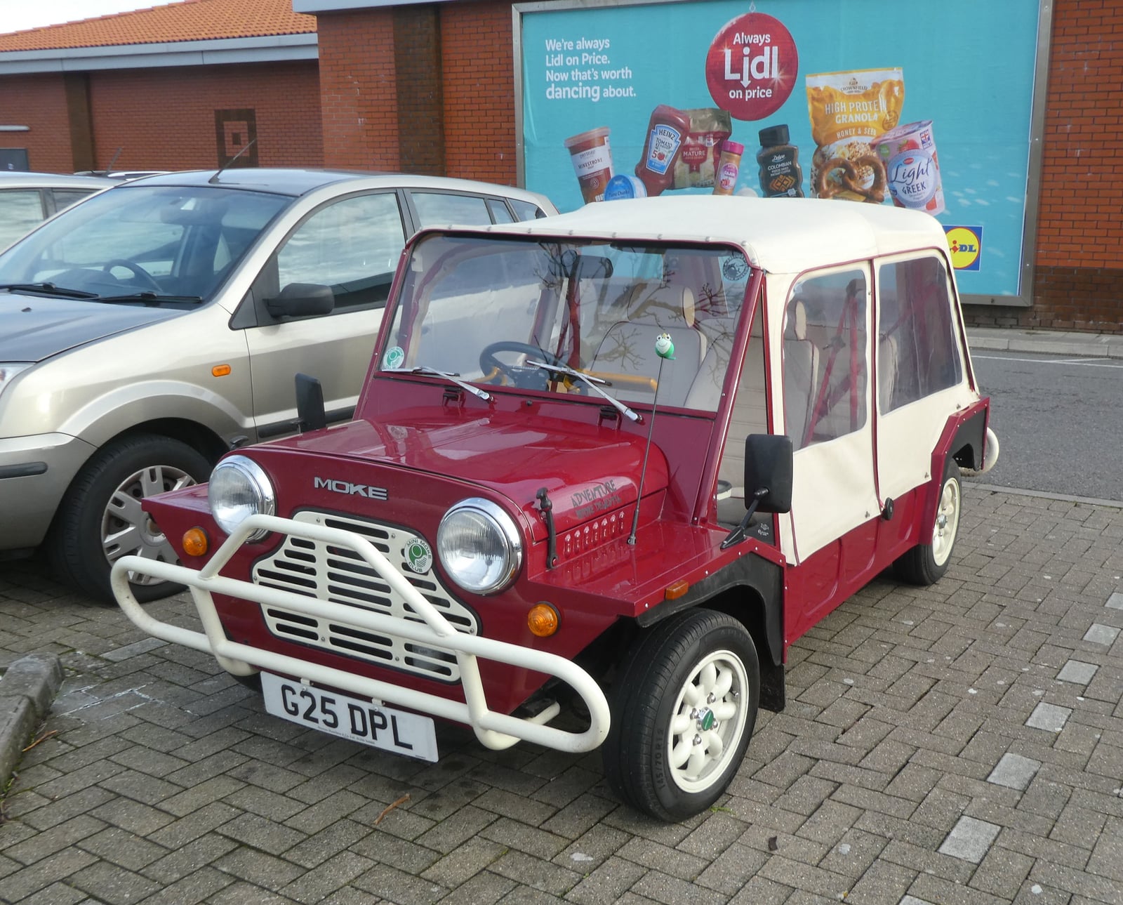 A red Mini Moke with a white top, front three-quarter view
