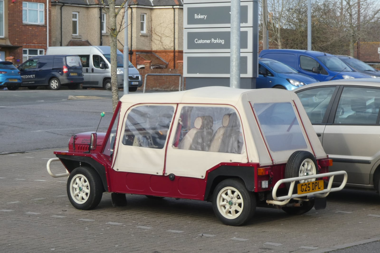 A red and white open Mini Moke with passengers
