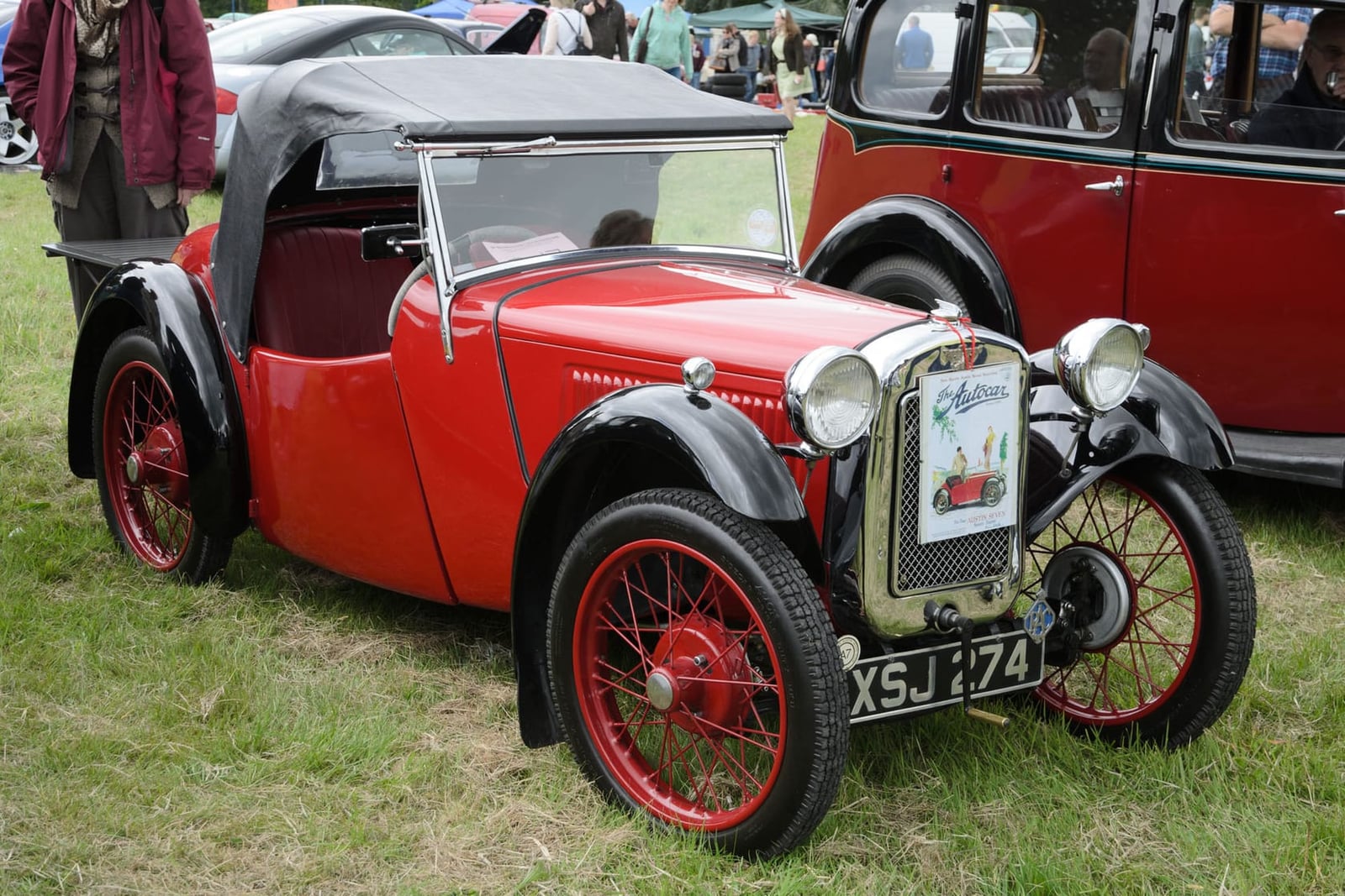 A red 1934 Austin Seven Nippy two-seater with red wire wheels and a UK registration at a show