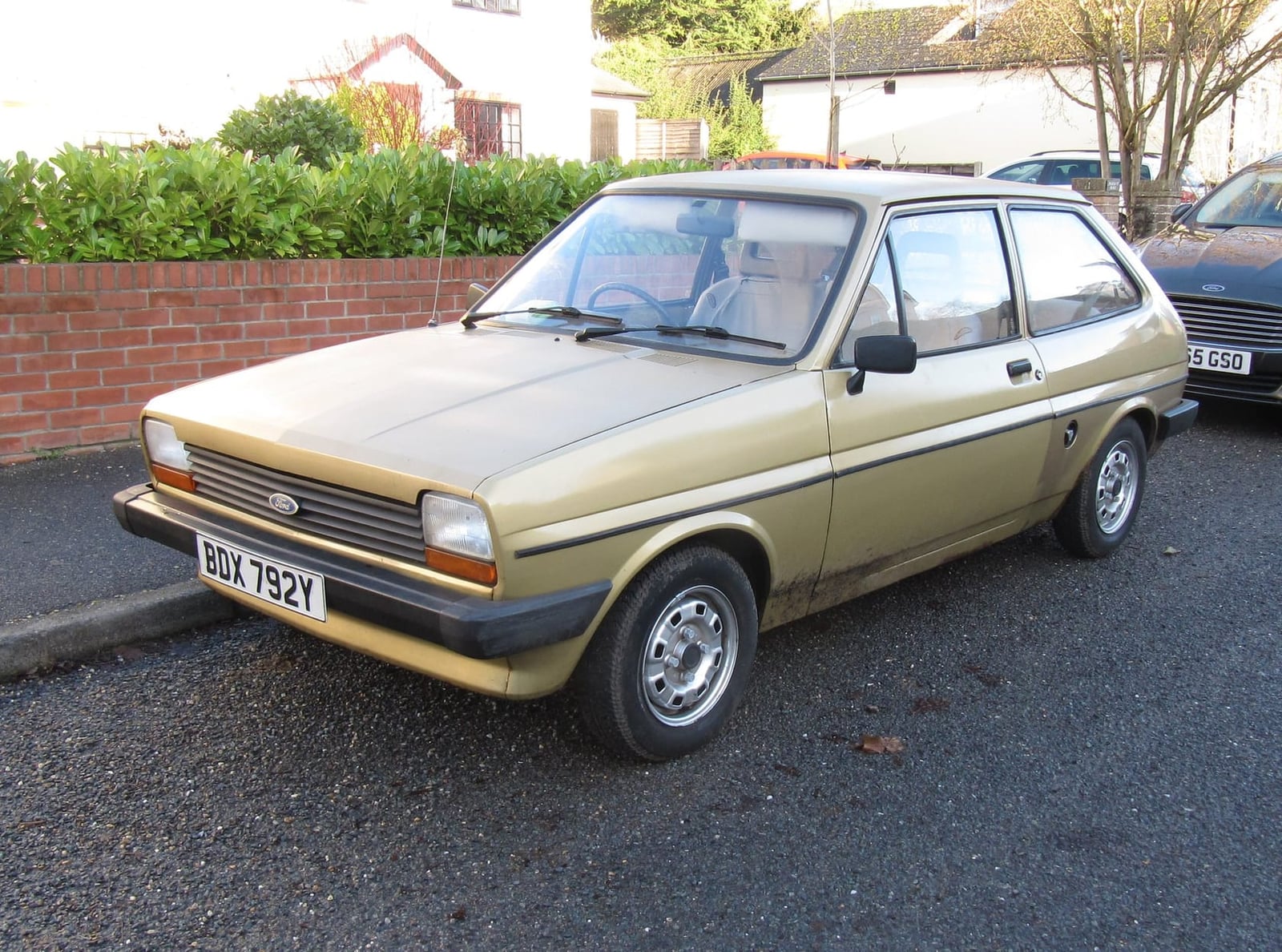 A gold Mk1 Ford Fiesta parked on a suburban street, front three-quarter view, UK registration BDX 792Y