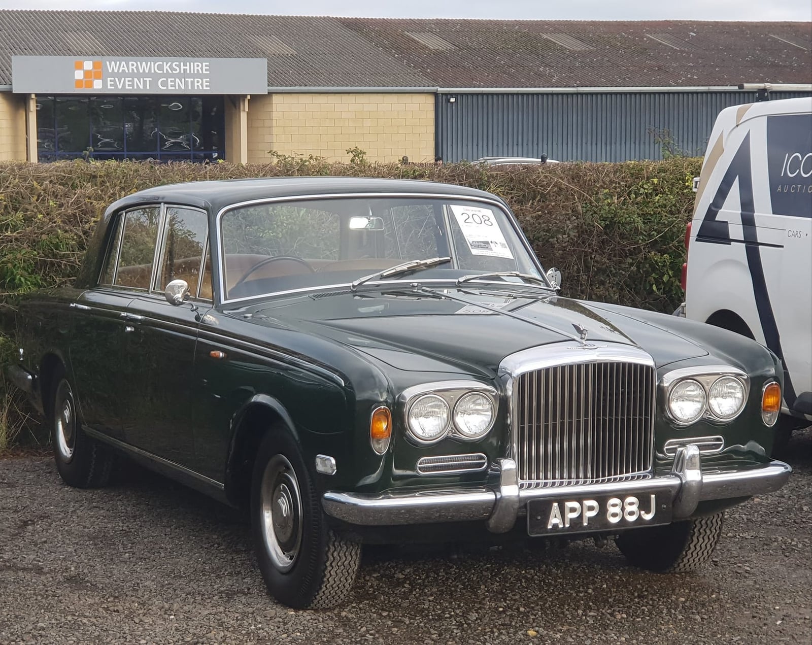 A dark green Bentley T1 with UK registration APP 88J outside an event centre