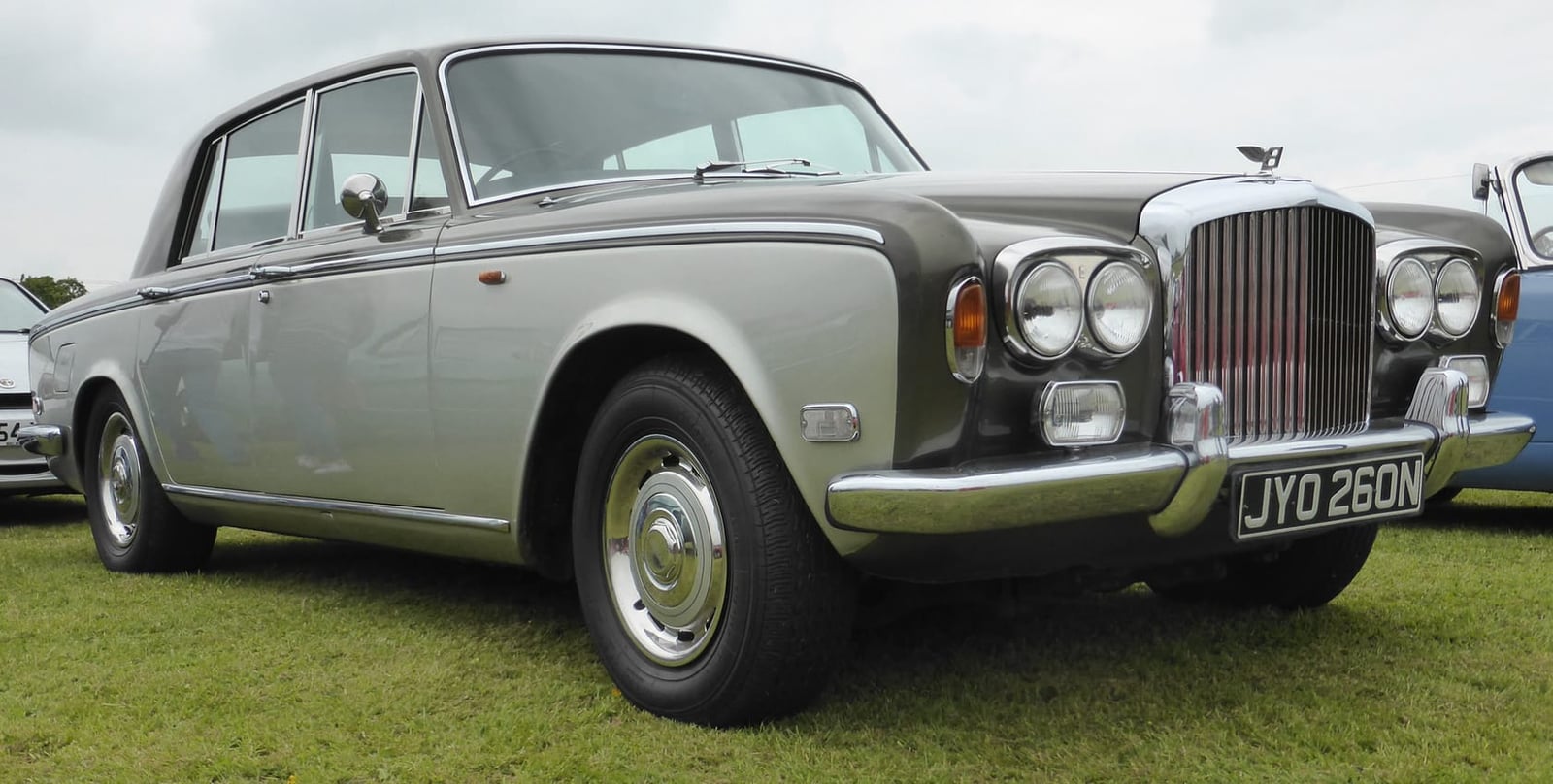 The side profile of a silver-green Bentley T1 saloon on a show field