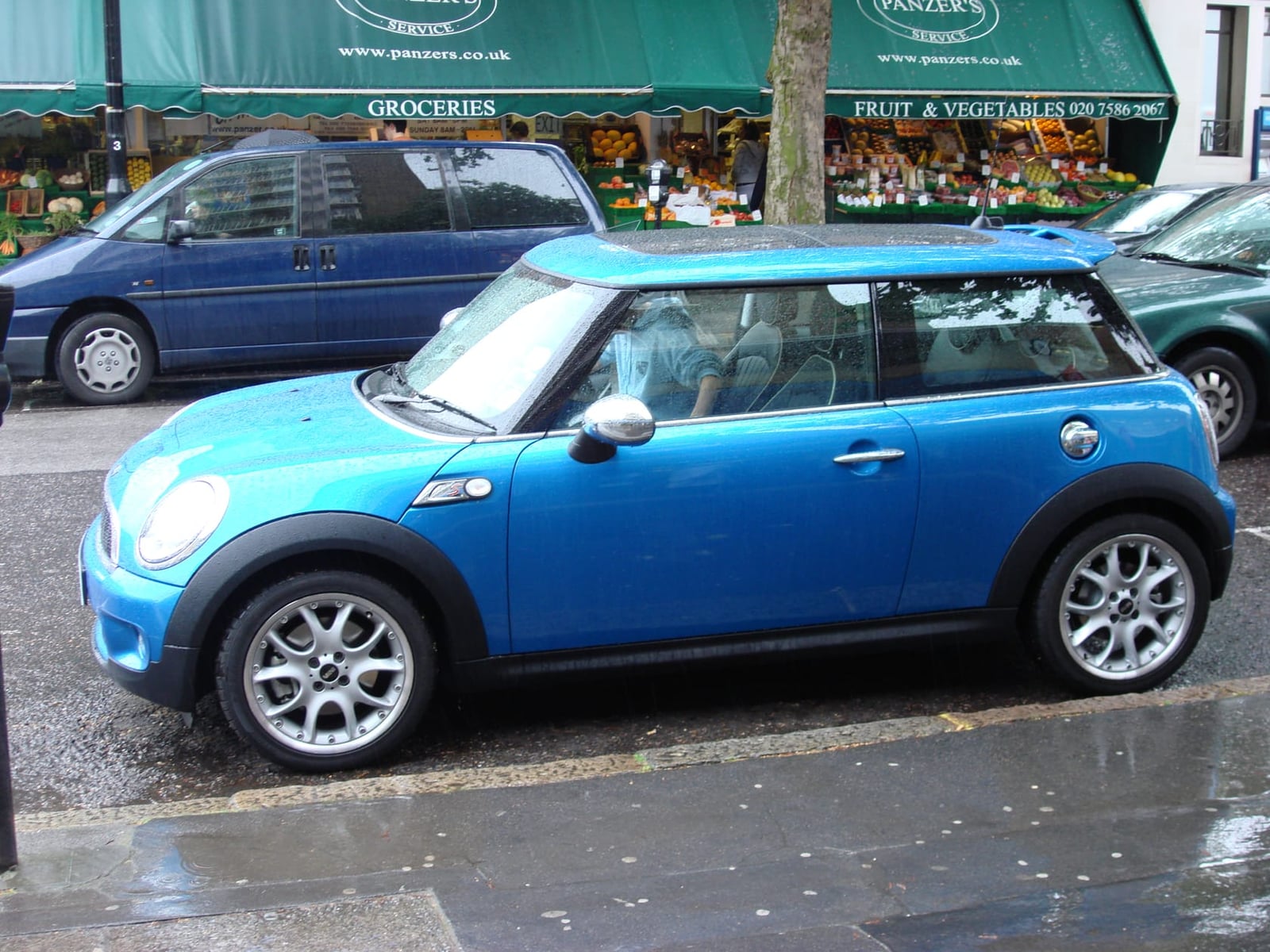 A bright blue MINI Cooper S R53 parked outside a greengrocer's shop on a London street