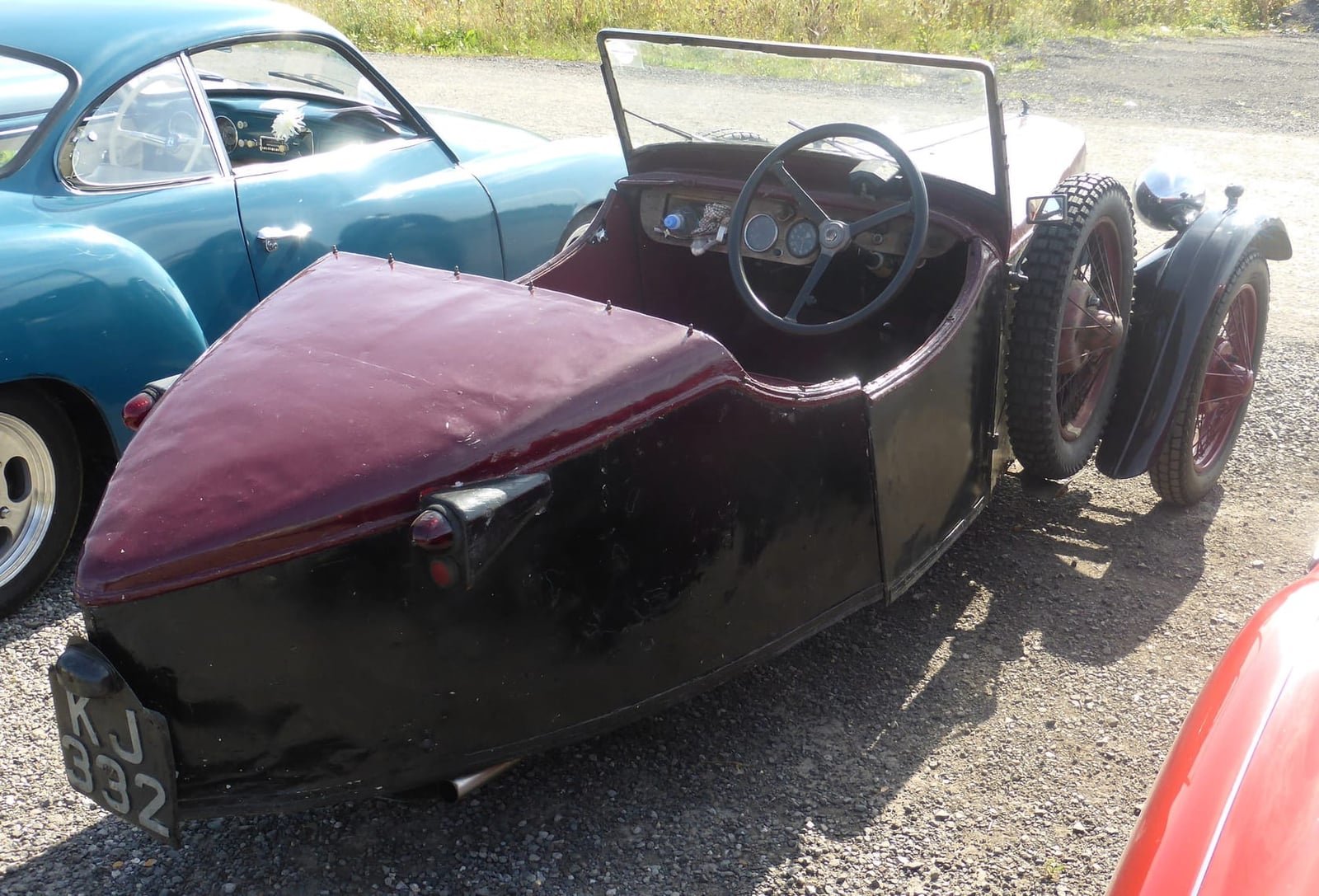The rear three-quarter of a maroon 1931 BSA three-wheeler showing its single rear wheel
