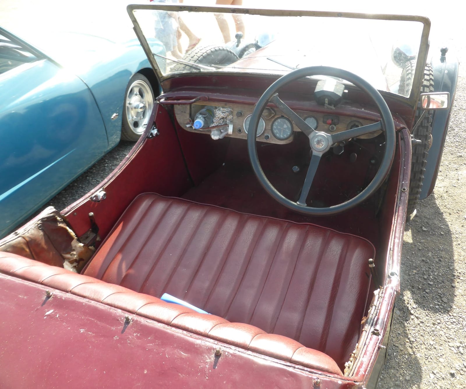 The open cockpit of a 1931 BSA three-wheeler with red upholstered bench seat and simple dashboard