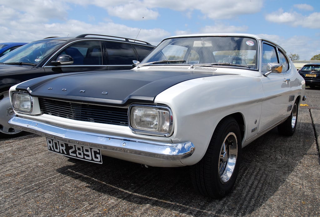 A white Ford Capri Mk1 with a matt-black bonnet at a British classic car show, UK registration ROR 289G