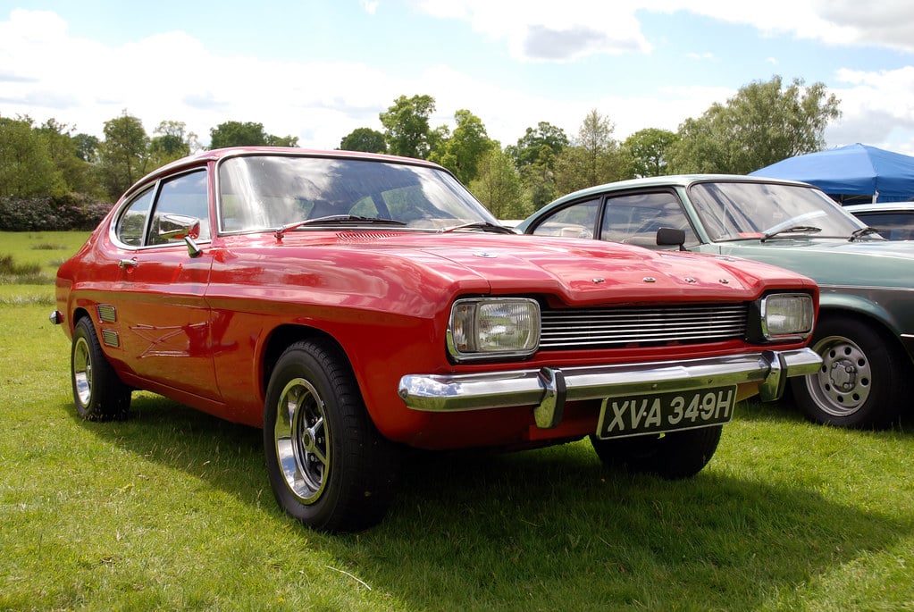 A red Ford Capri Mk1 with chrome bumpers on grass at a British classic car show, UK registration XVA 349H