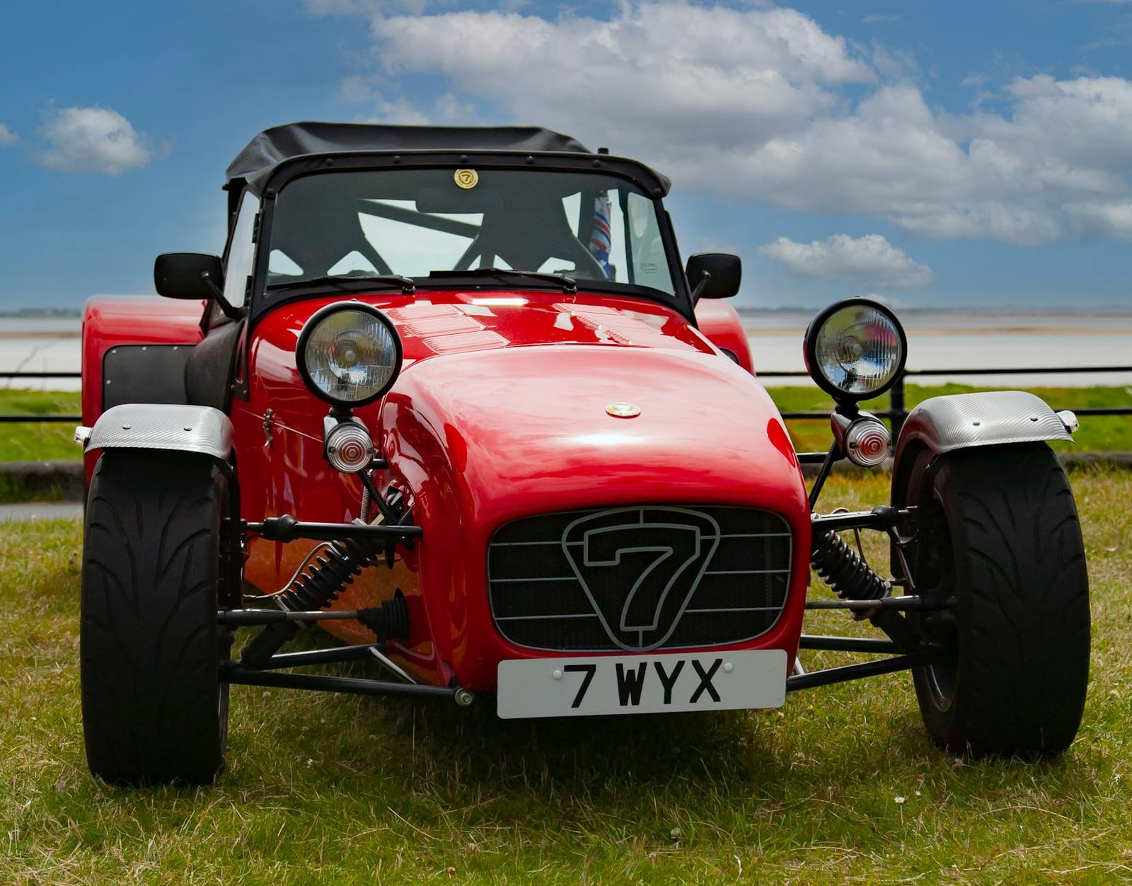 A red Caterham Seven lightweight sports car on grass
