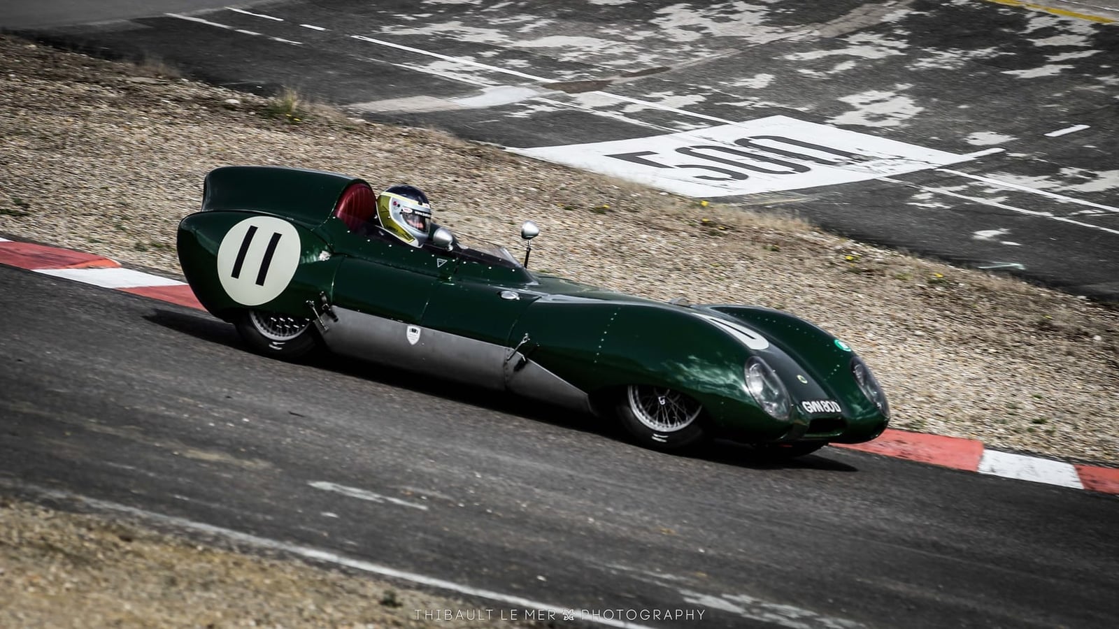 A green Lotus Eleven carrying race number 11 cornering on a race circuit