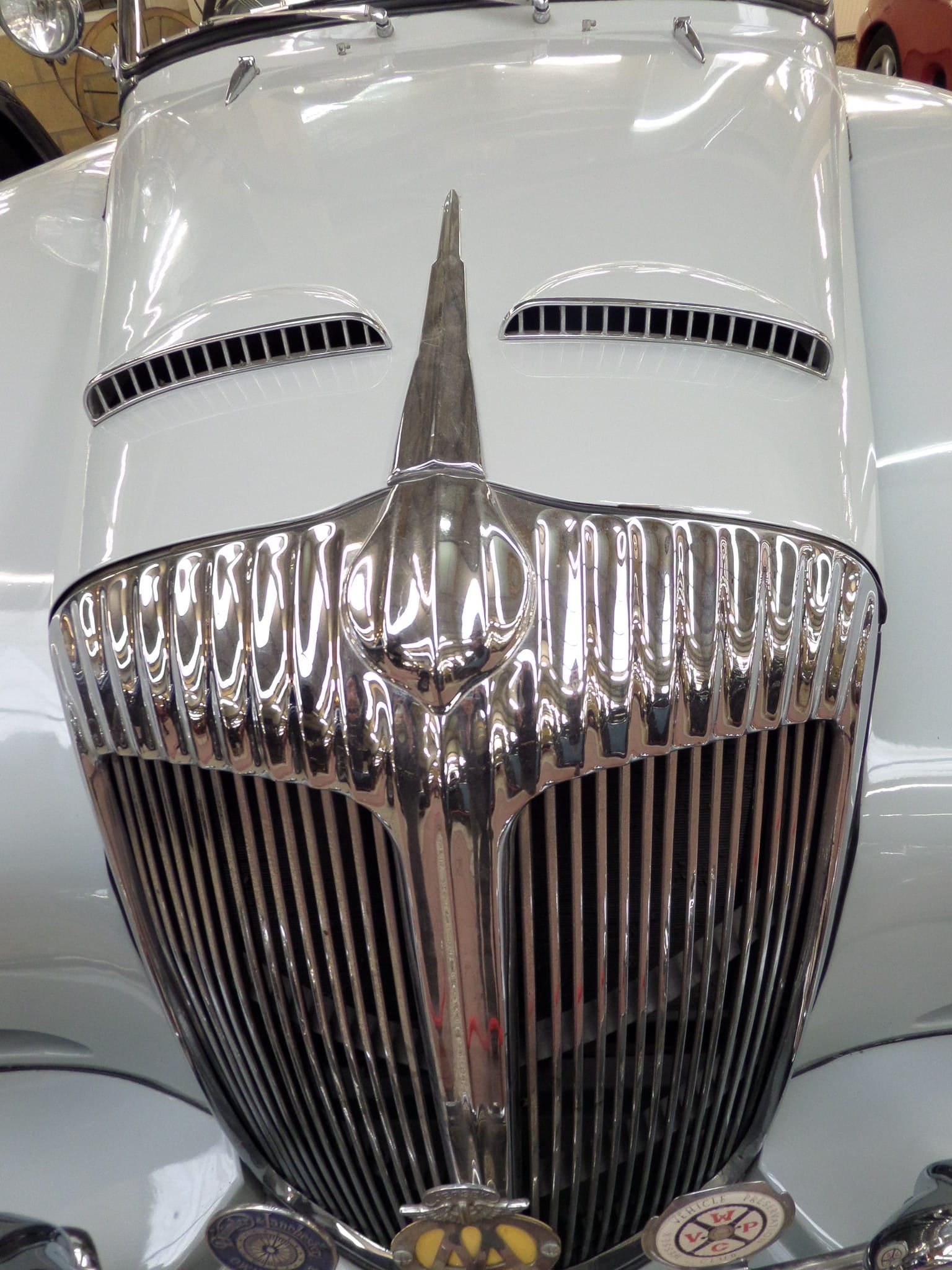 A grey Daimler Conquest Roadster with a dark blue drophead beside it on indoor display