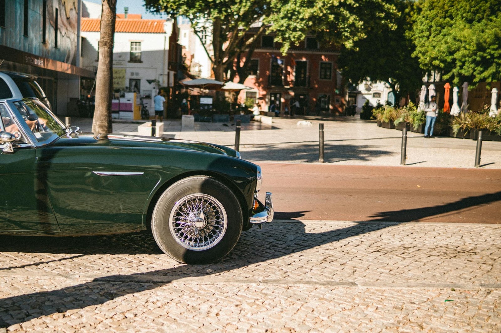 A dark green Austin-Healey 3000 parked on a sunny street