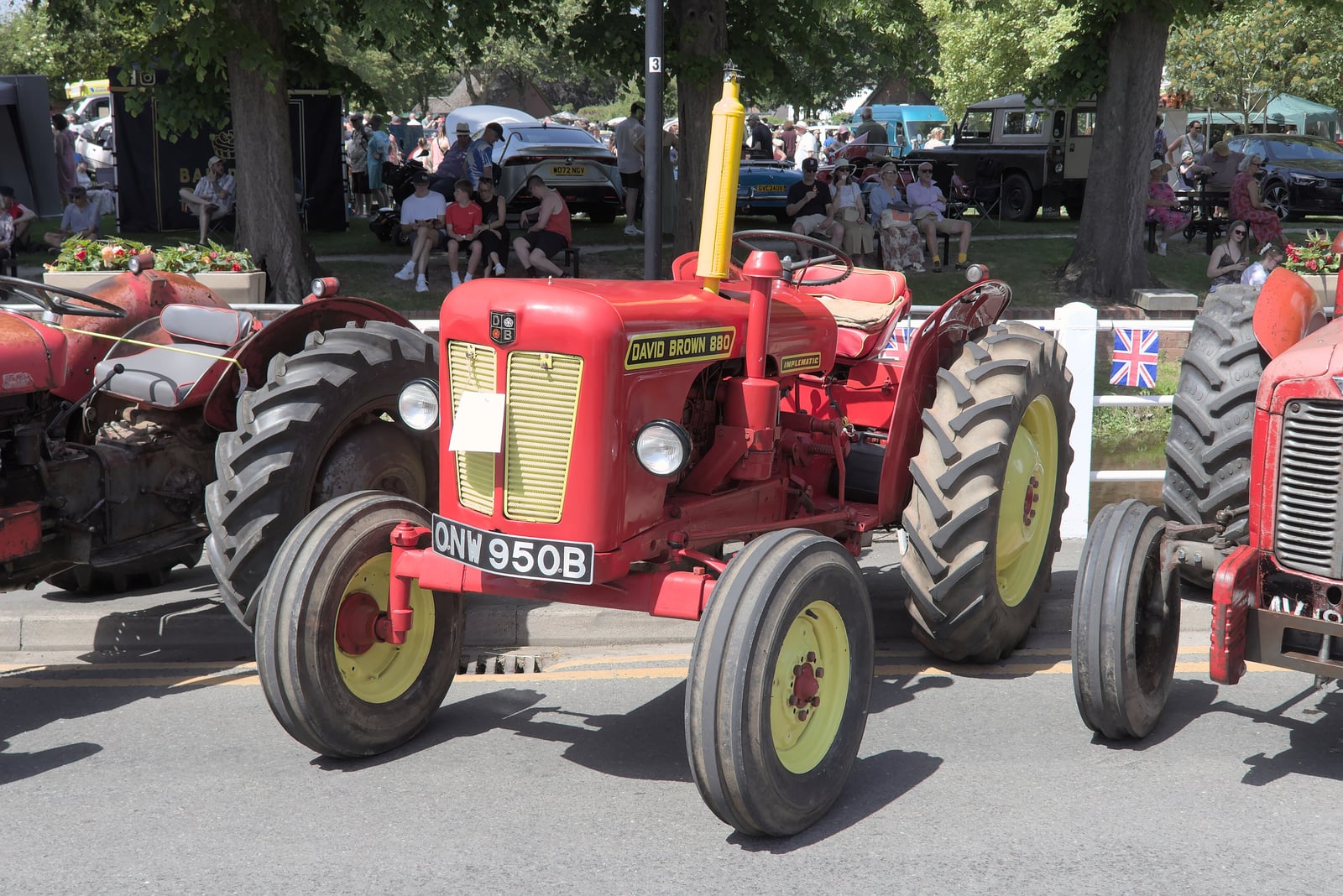 A red David Brown 880, registration ONW 950B, in a village fete parade with bunting and crowds