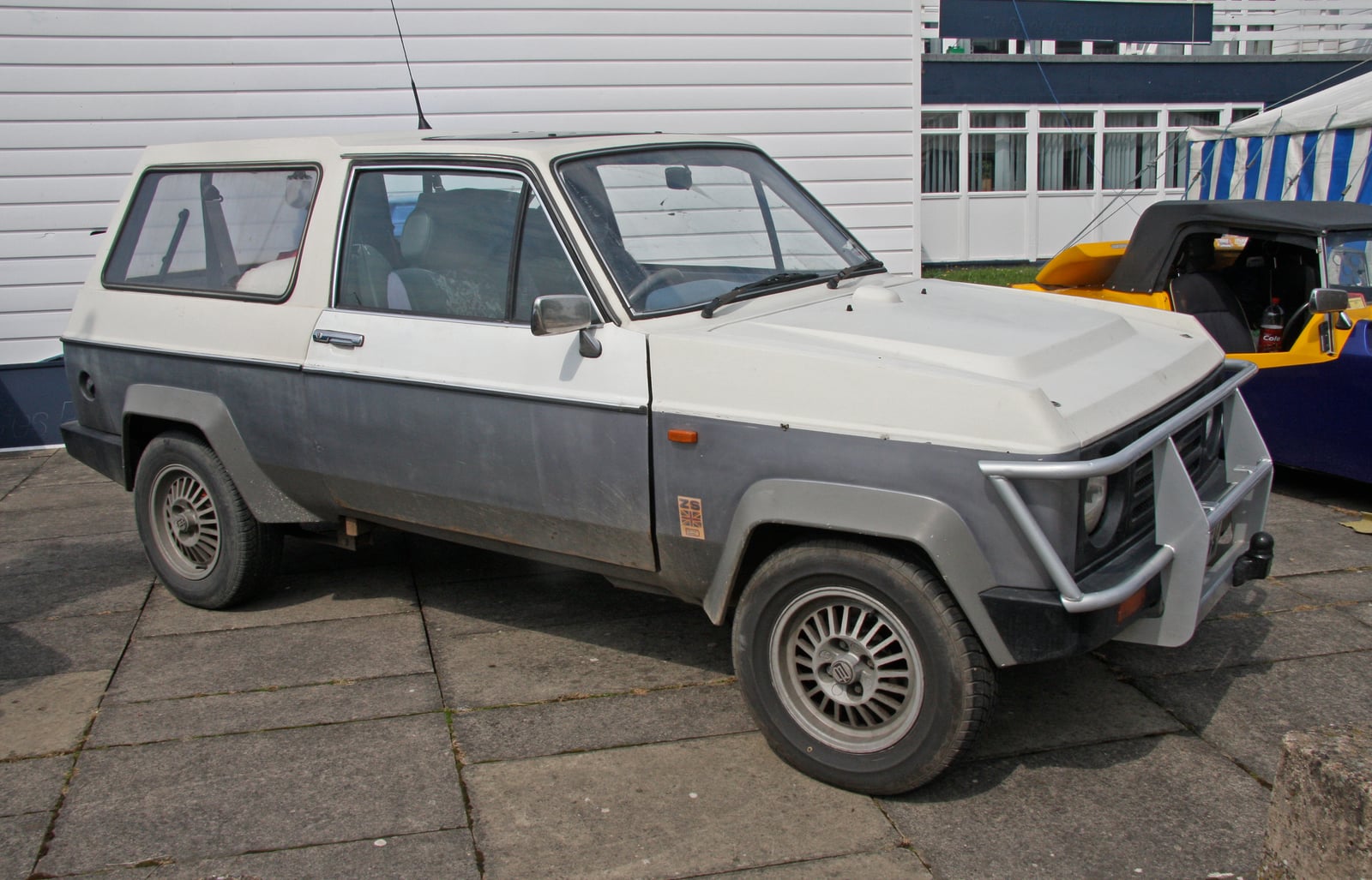 A beige Dutton Beneto, an SUV-styled kit car, on grass at a show