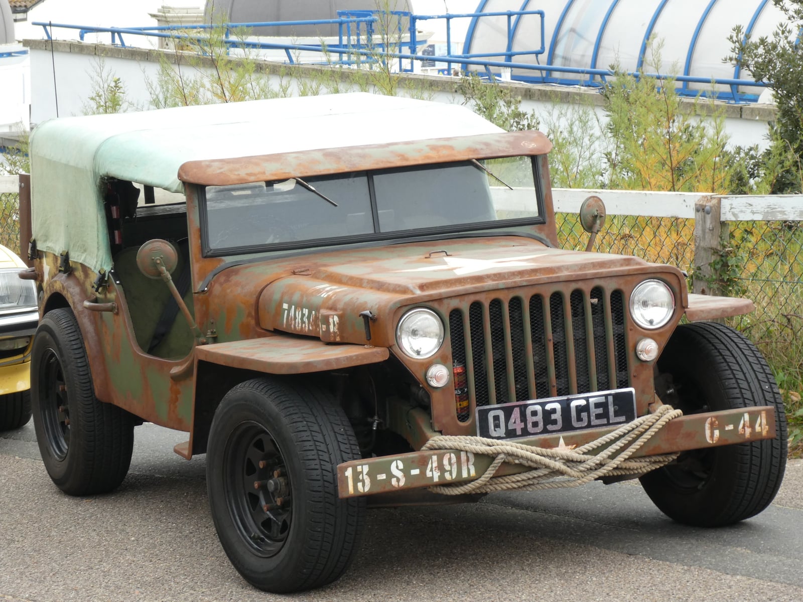 A weathered military-style Jeep replica in faded olive green with surface rust, front three-quarter view, wearing the UK Q-prefix registration plate Q483 GEL
