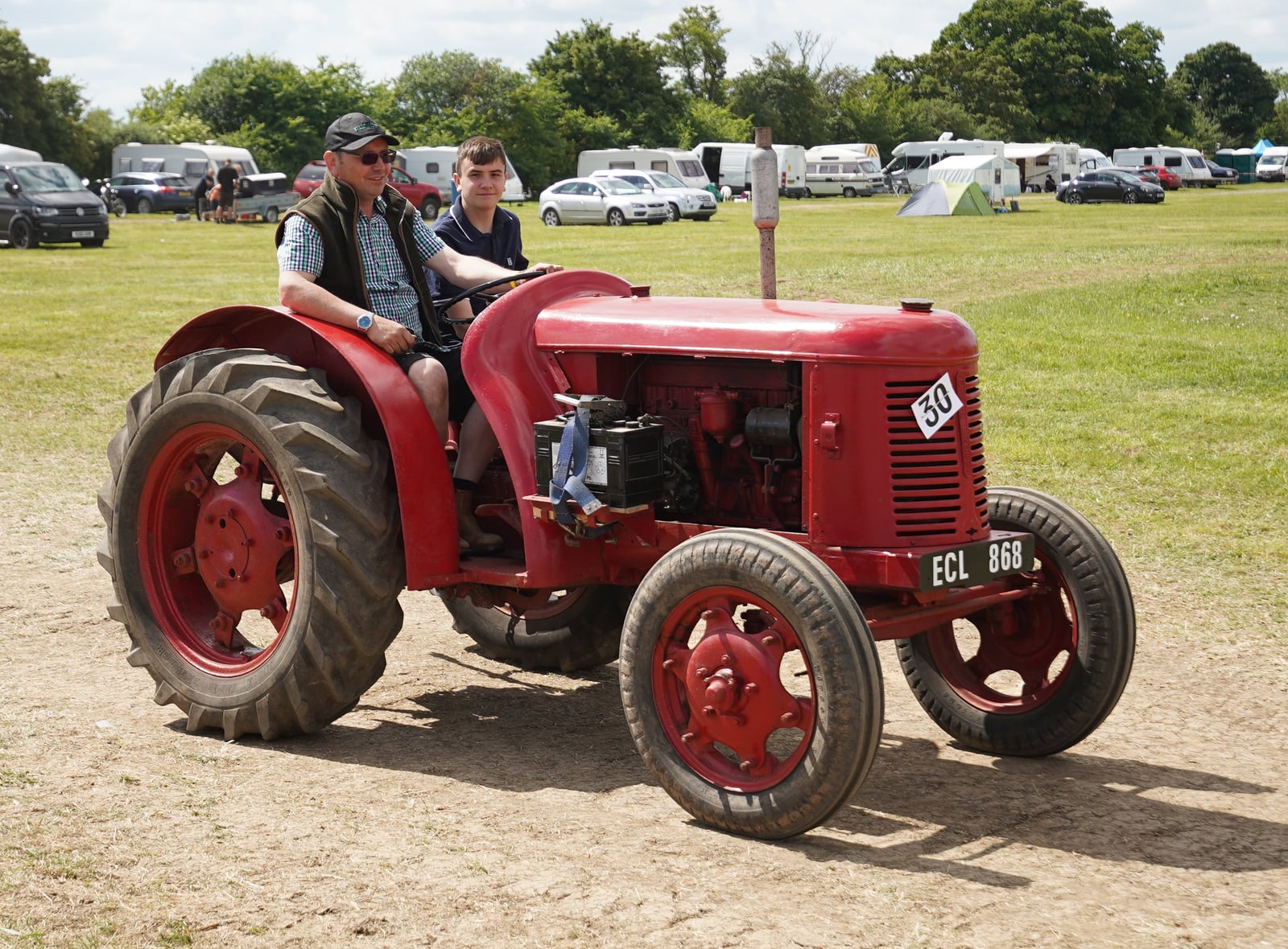 A red 1948 David Brown Cropmaster, registration ECL 868, being driven at a steam fair with two riders