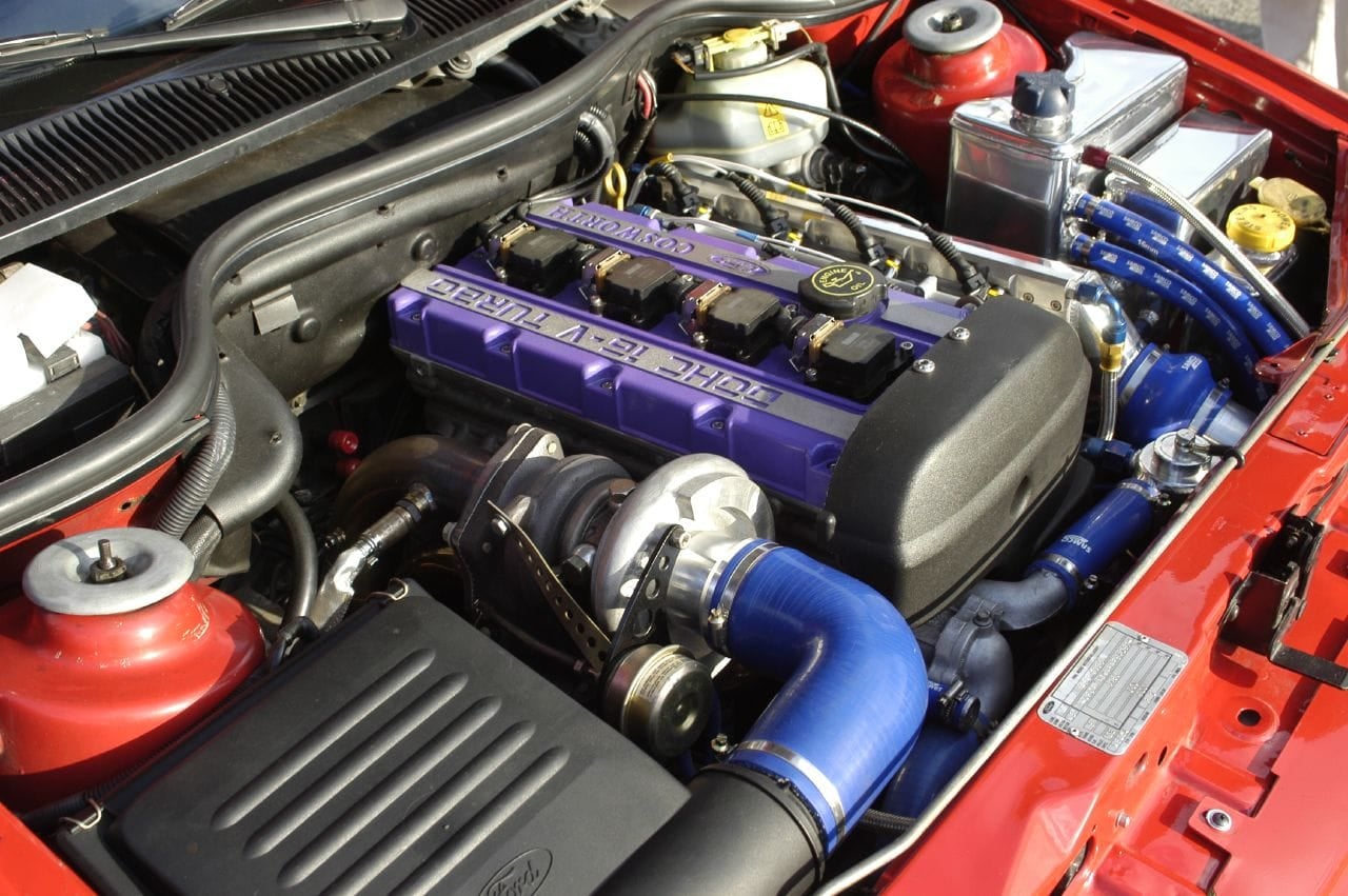 The engine bay of a Ford Escort RS Cosworth showing the turbocharger, intercooler pipework and Cosworth cam cover