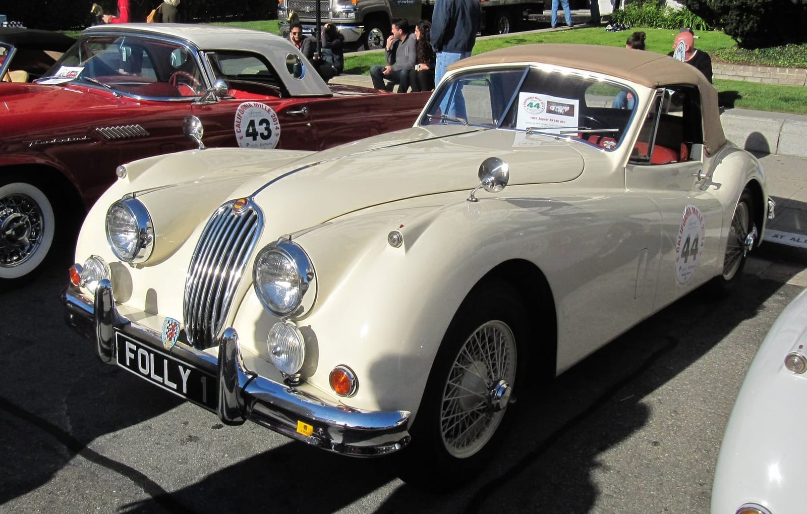 A cream Jaguar XK140 drophead coupé with its hood up and a UK registration on a rally