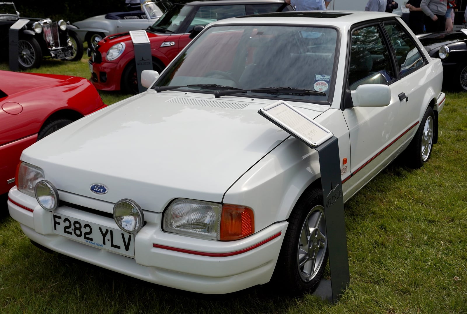 A white Ford Escort XR3i hatchback at a show, front three-quarter view