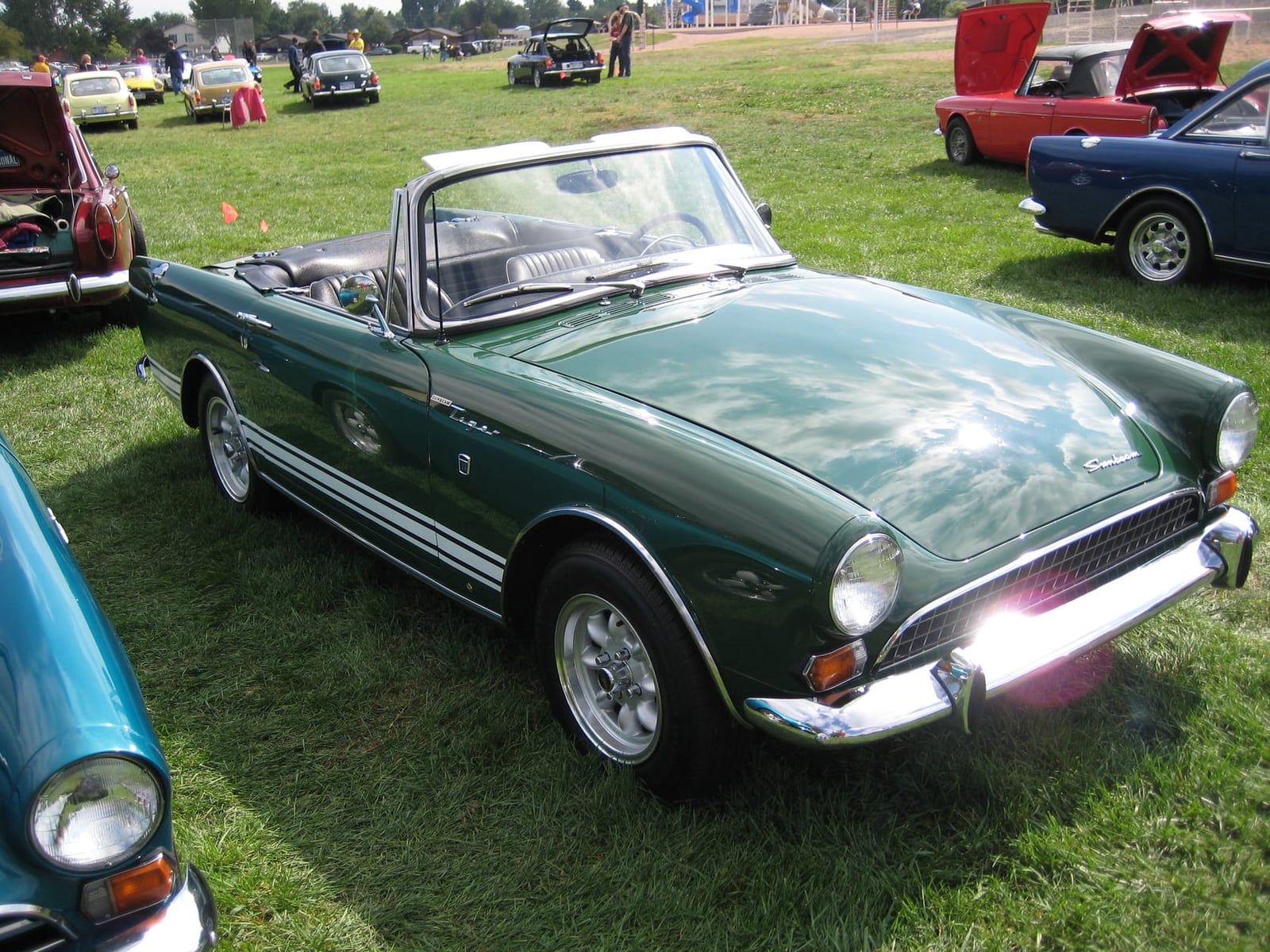 A dark green Sunbeam Tiger with the top down leading a row of Tigers on a showfield