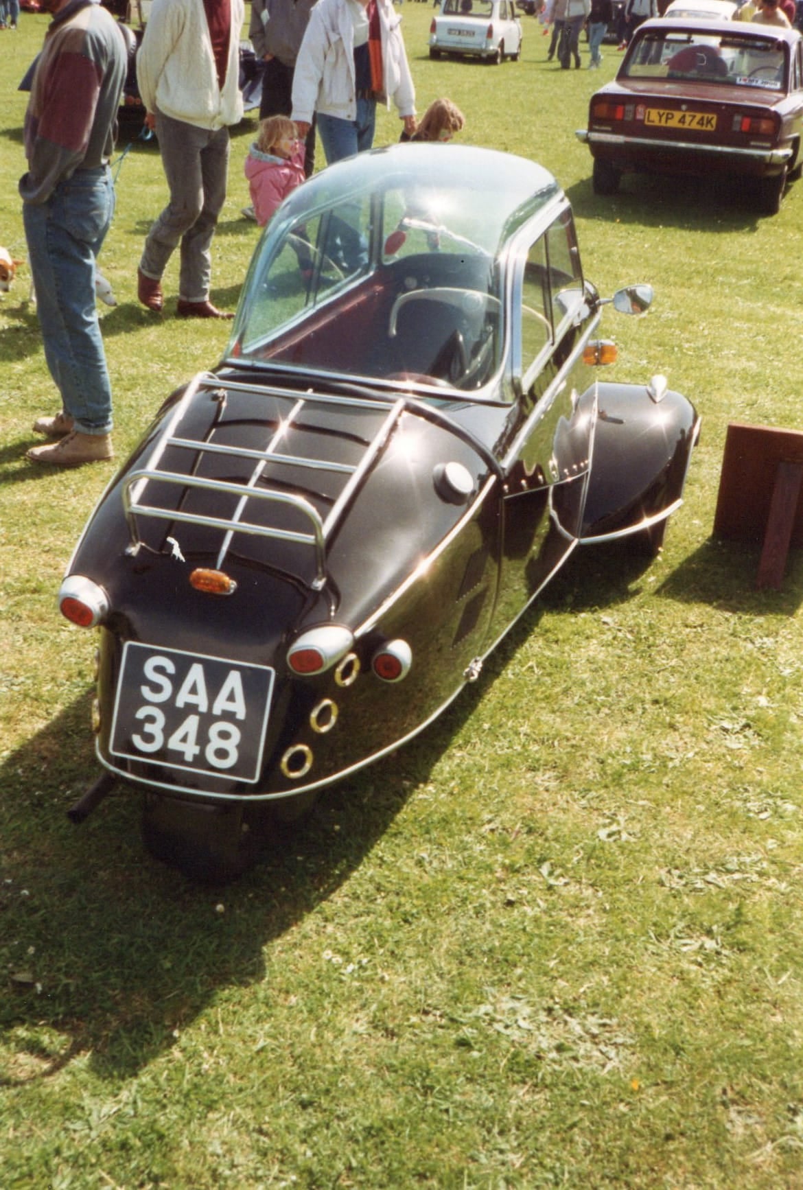 A dark Messerschmitt Kabinenroller on grass at a British classic vehicle show, rear three-quarter view, UK registration SAA 348