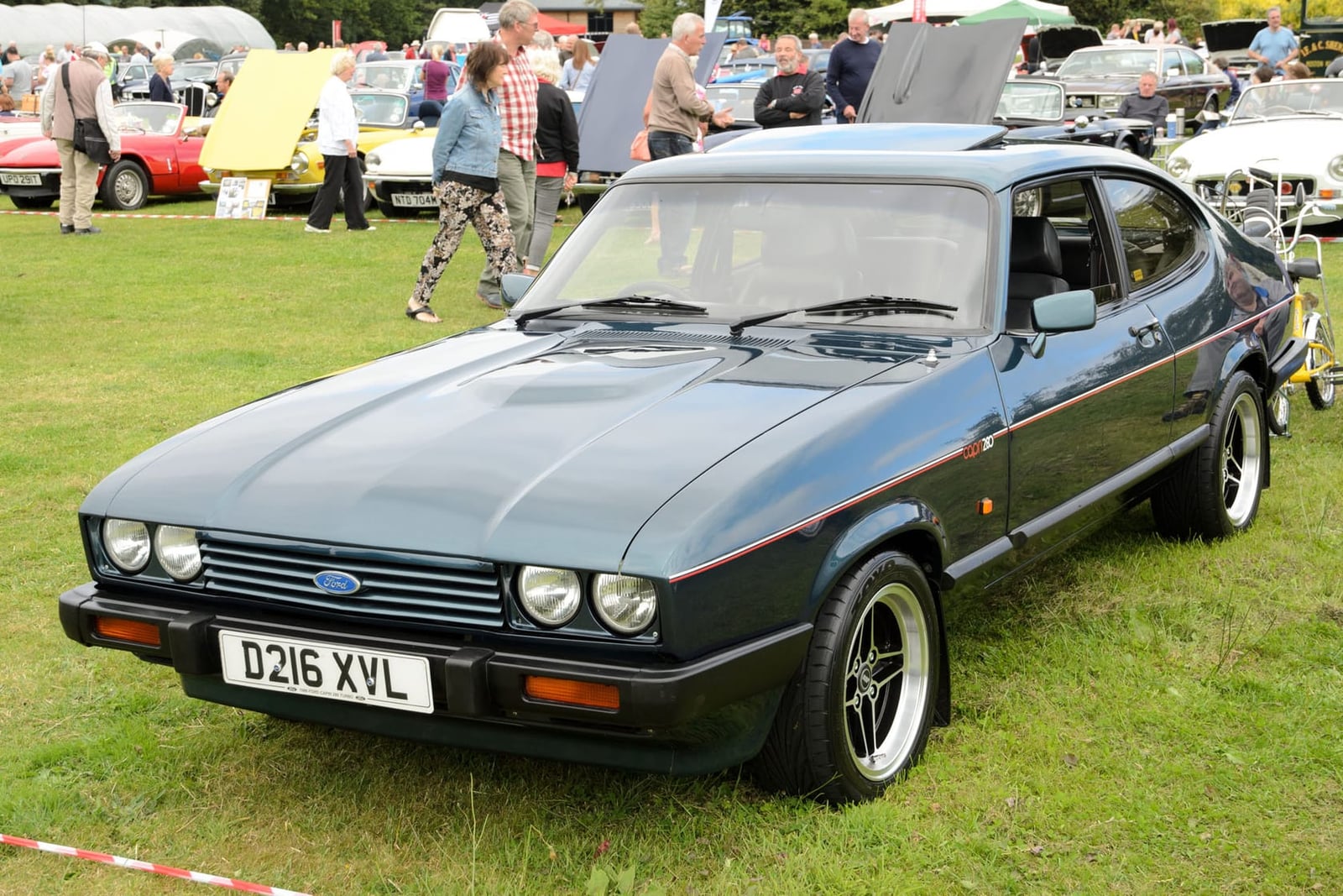 A Brooklands Green 1987 Ford Capri 280 with a UK registration and seven-spoke alloy wheels on a show field