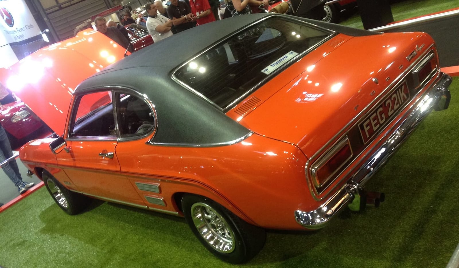 The rear of an orange 1972 Ford Capri Mk1 3000E with a black vinyl roof on a show stand